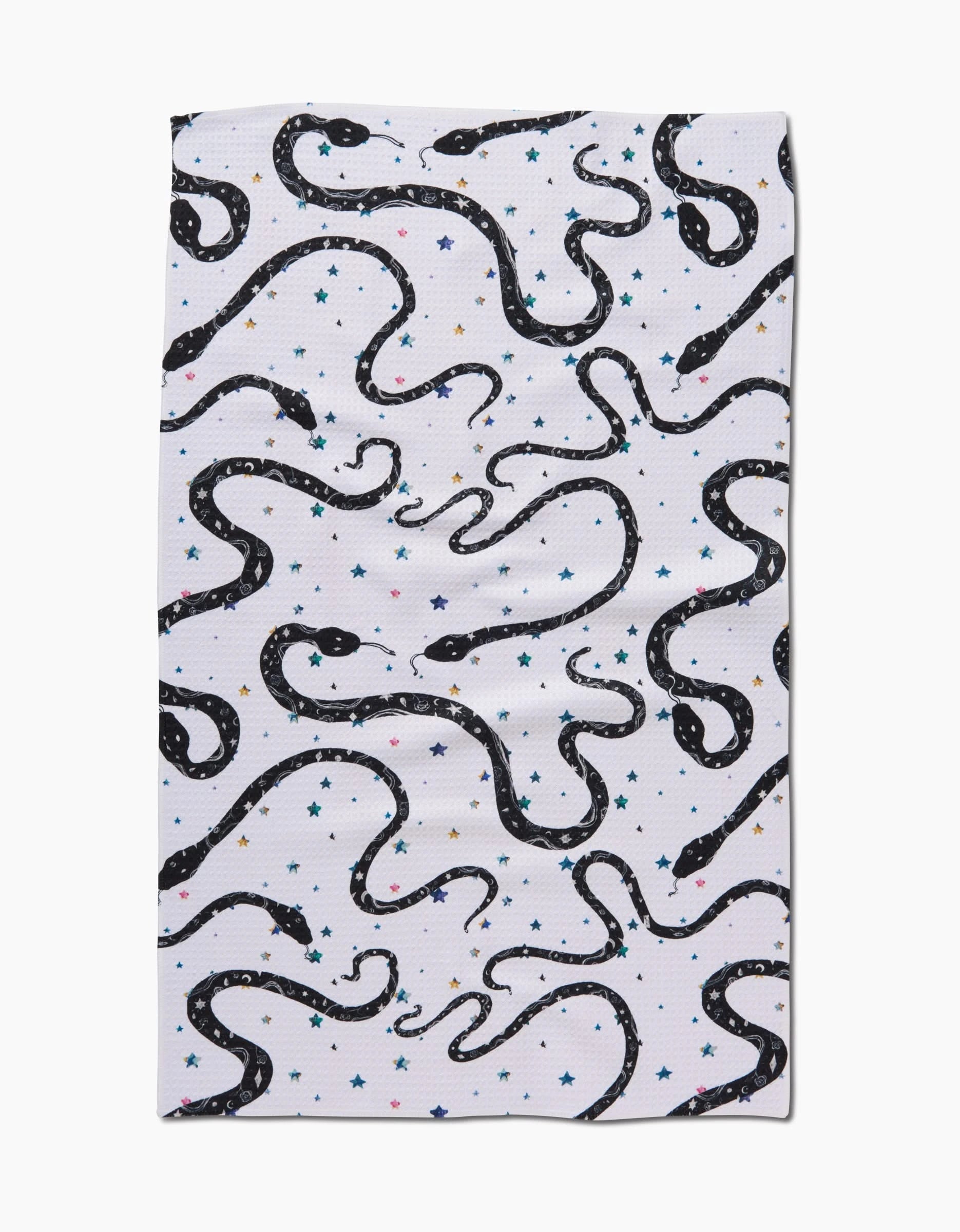 The Cosmic Snakes tea towel by Pascale Dilger is made from recycled materials and features black snakes and colorful stars on white fabric, shown laid out flat.
