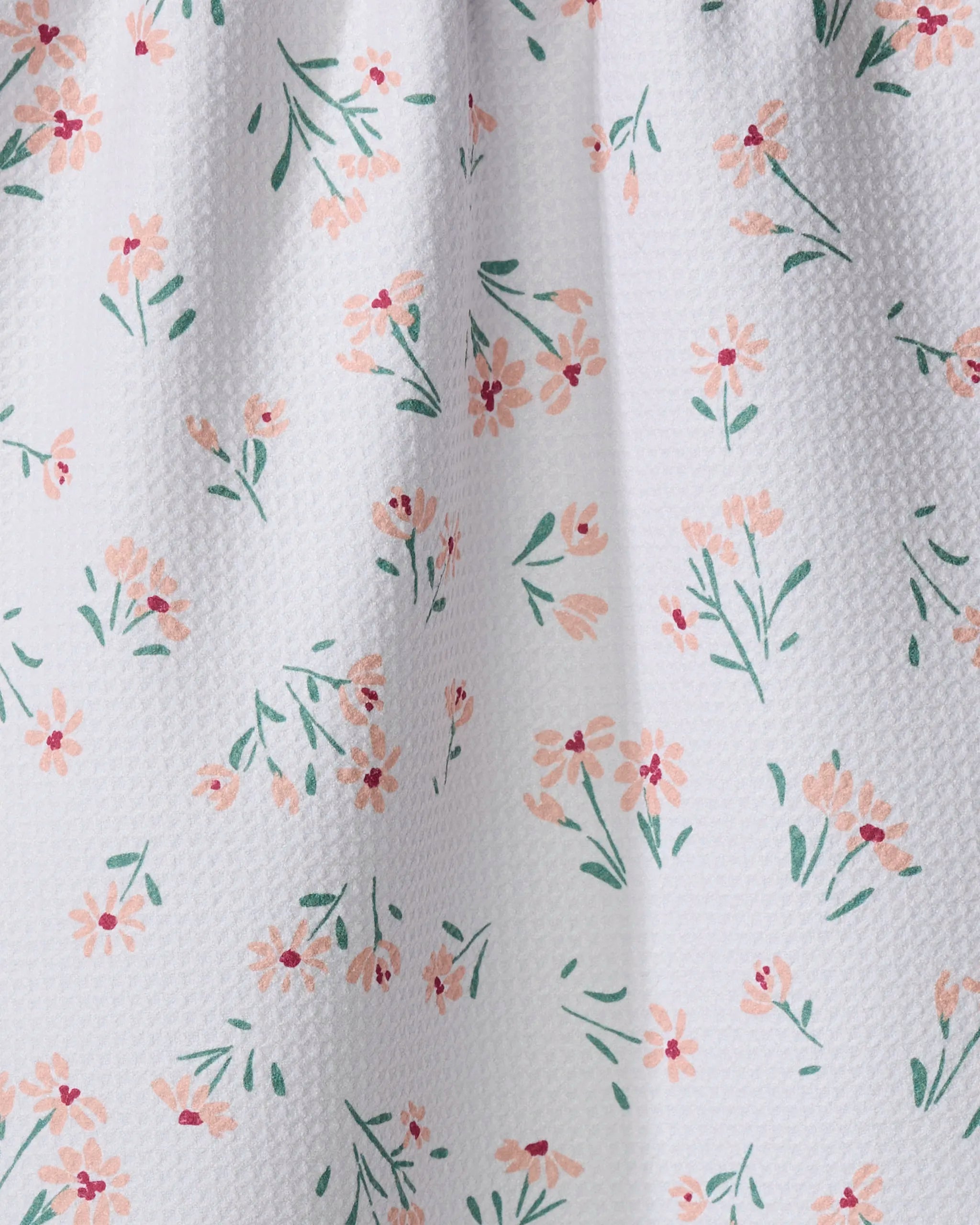The Cottage Garden tea towel by Hufton Studio features a white textured fabric with small light pink and peach flowers and green stems. The ultra-absorbent material is shown in gentle folds.