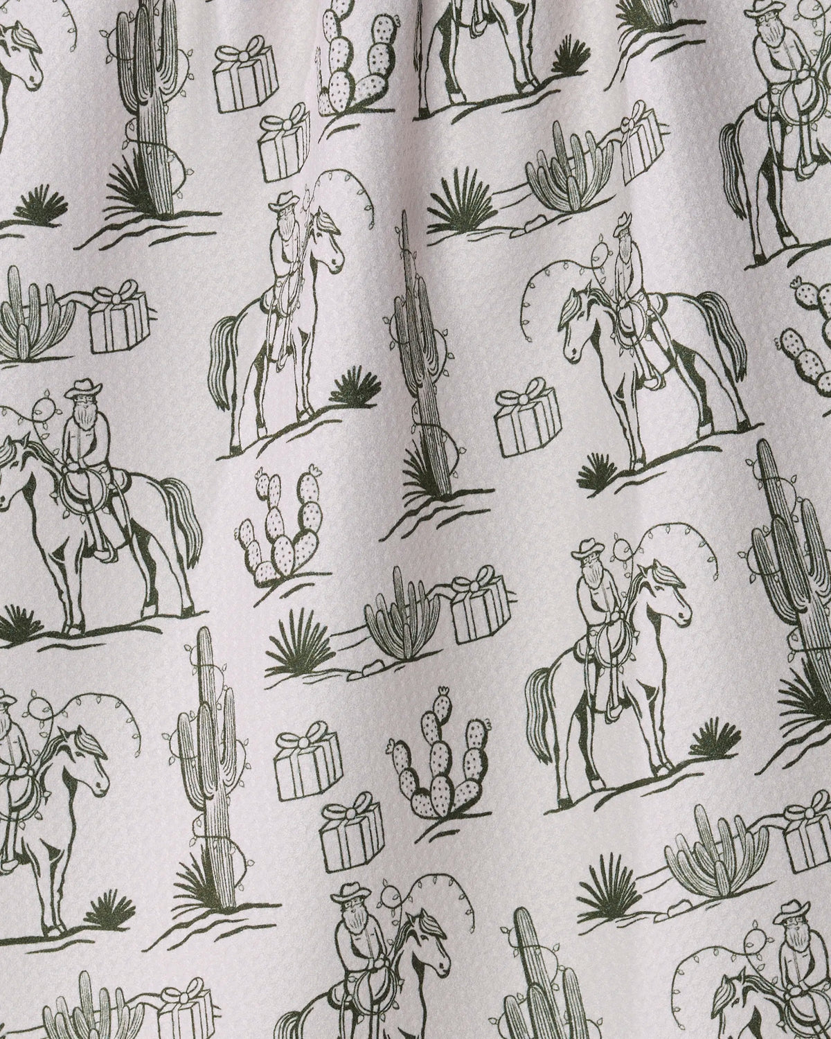 Cowboy Claus by Geometry features a patterned fabric with repeated line drawings of cowboys on horses, cacti, agave, and small wrapped gift boxes—all in greenish tones on a light background. Perfect as an ultra-absorbent kitchen or tea towel, this design is also available in recycled materials for an eco-friendly touch.