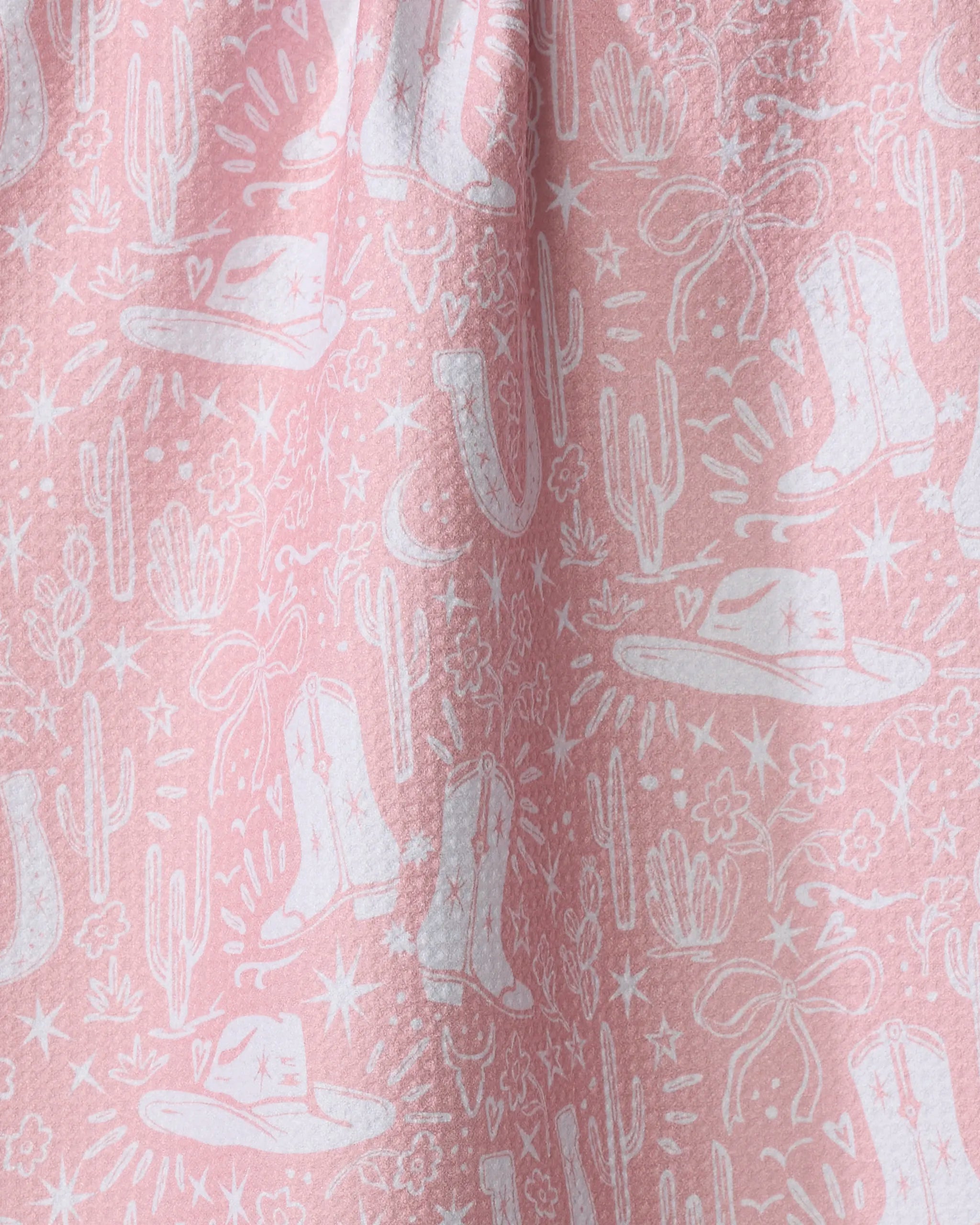 Add a touch of flair to your kitchen with the Cowgirl Chic dish towel by Aubrey Fairchild. This pink, absorbent towel features a white western motif with cowboy hats, boots, cacti, stars, and lassos in softly gathered folds.