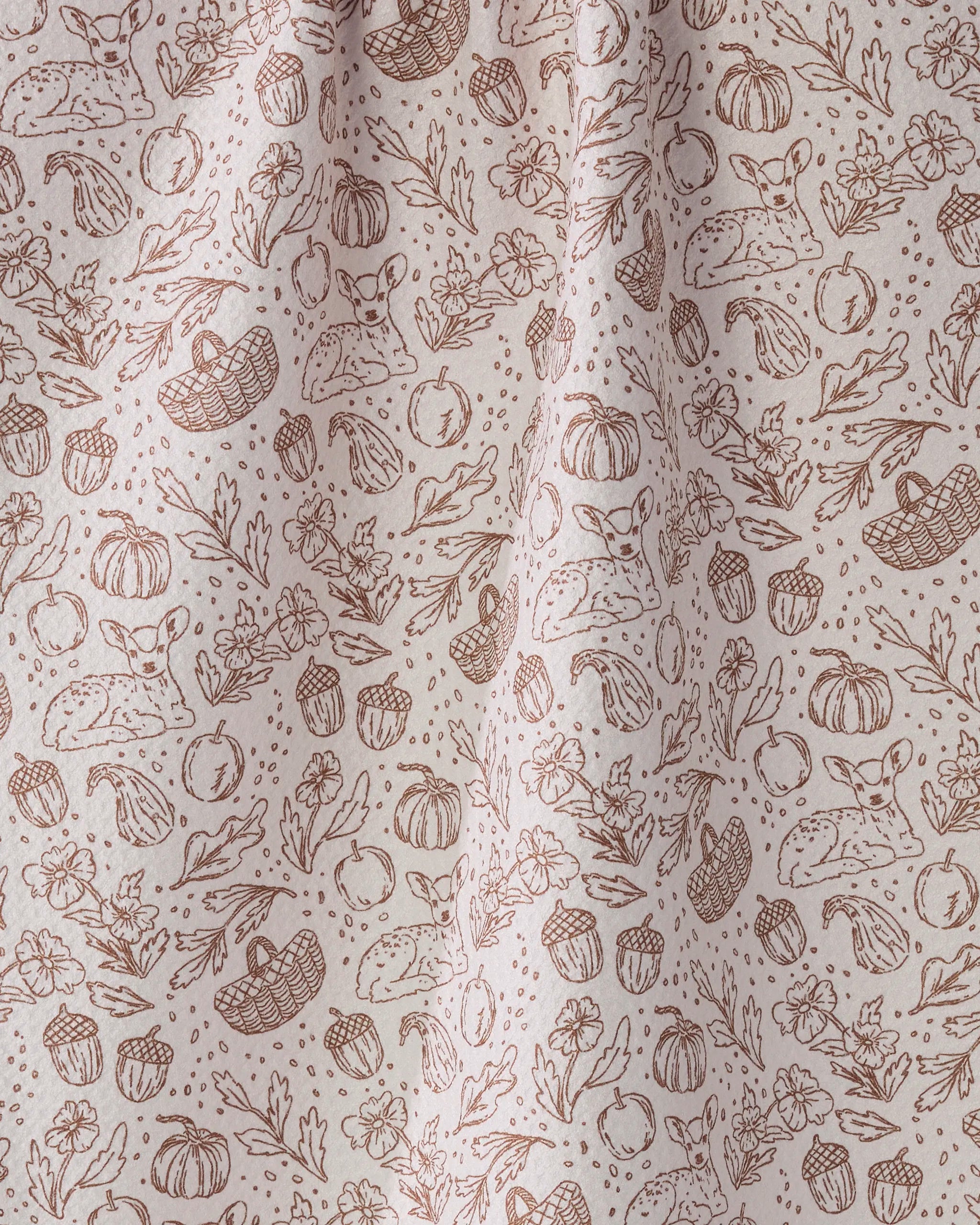 Cozy Flora by Geometry features a beige fabric with a brown, whimsical pattern of deer, pumpkins, flowers, apples, and more—making this ultra-absorbent kitchen tea towel both charming and practical.