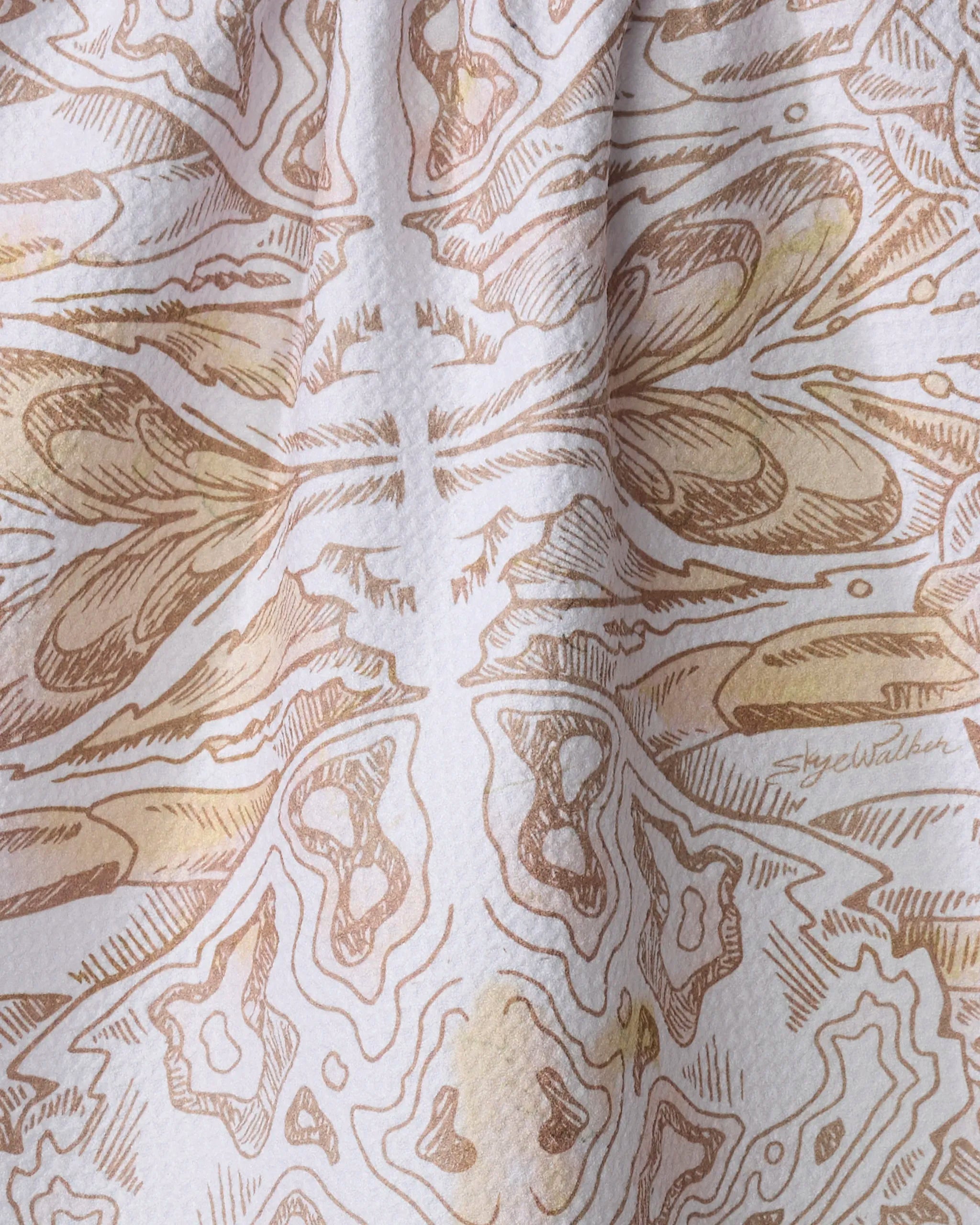 Close-up of Skye Walker’s “Crab” eco-friendly kitchen towel, showing an absorbent, slightly wrinkled fabric with a detailed brown and beige crab pattern and the artist’s signature faintly visible on the right.