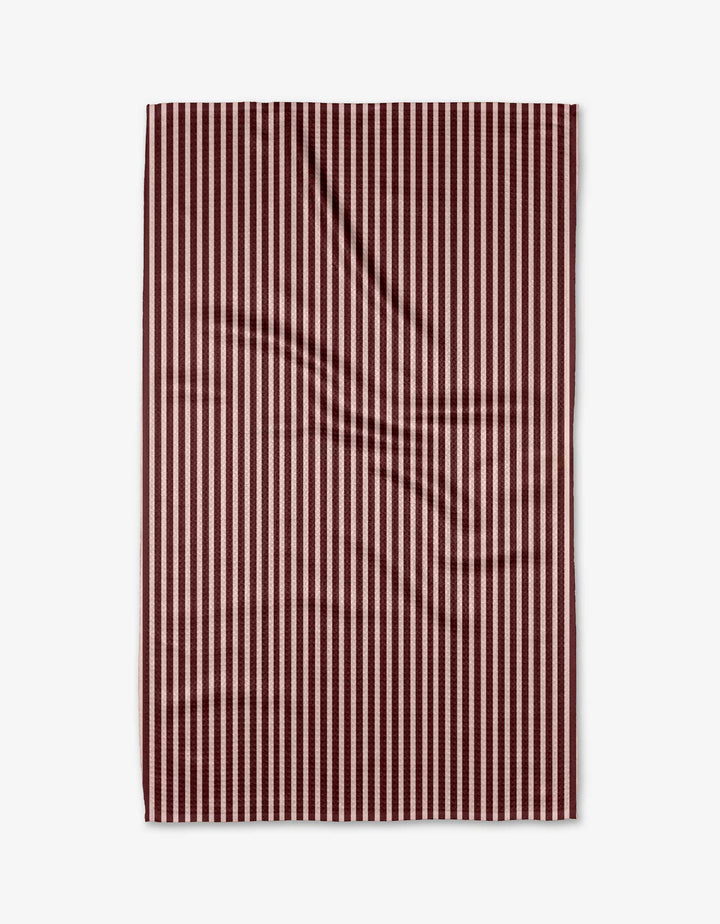 The Kelsi Fullmer Cranberry Stripe towel is rectangular, ultra-absorbent, and features vertical maroon and white stripes. It’s shown laid flat on a white background with minor creases visible.