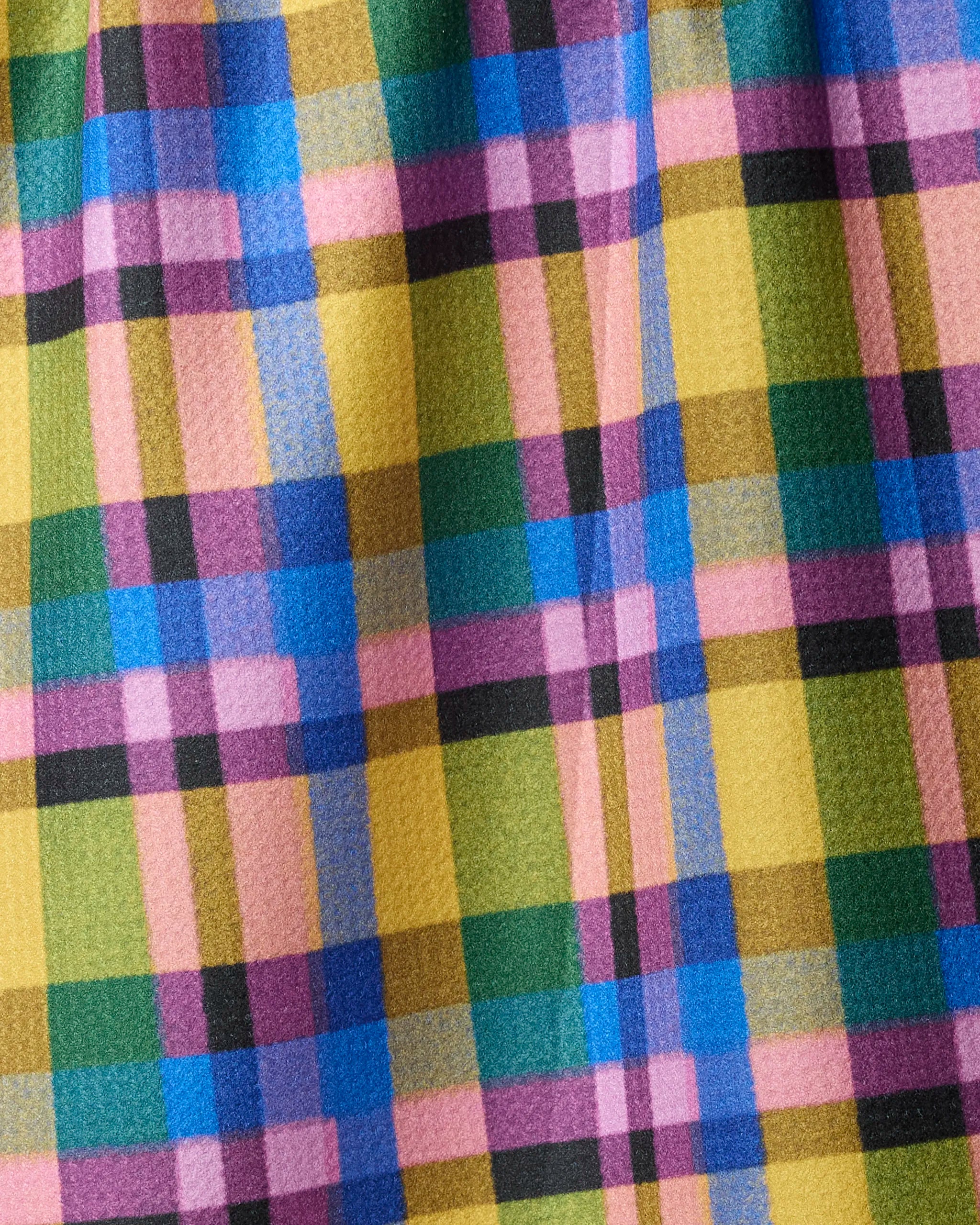 A close-up of Geometry’s Crayon tea towel showcases a vibrant checkered pattern with colorful plaid stripes—crafted from quick-drying recycled materials.