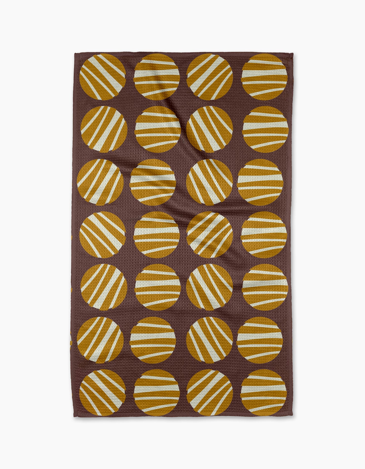 The Crazy Circles tea towel by Lizzie Clark is brown and rectangular, featuring a grid of evenly spaced yellow and white striped circles with diagonal stripes on its ultra-absorbent surface.