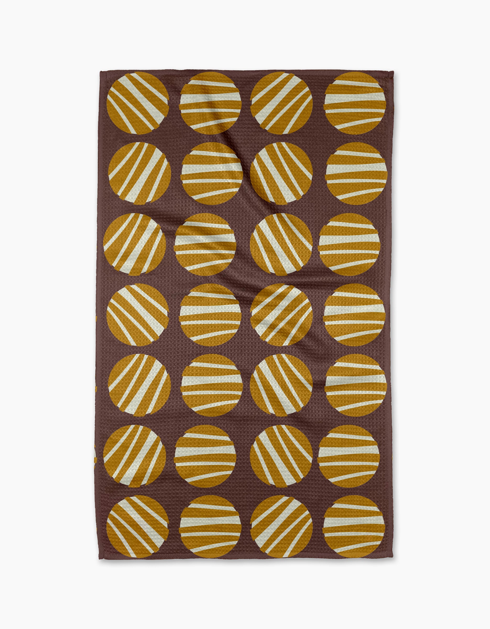 The Crazy Circles tea towel by Lizzie Clark is brown and rectangular, featuring a grid of evenly spaced yellow and white striped circles with diagonal stripes on its ultra-absorbent surface.