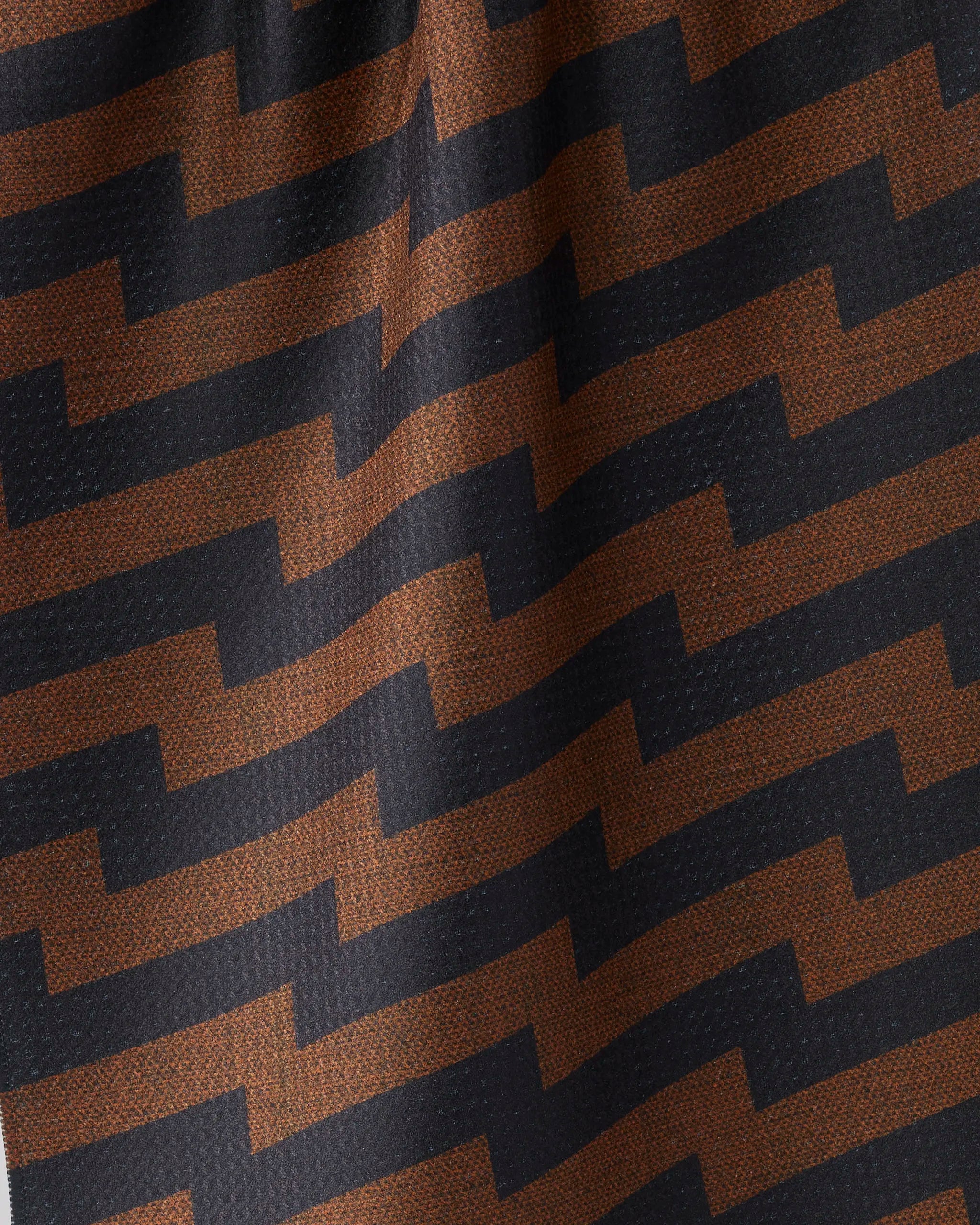 Close-up of the Geometry "Current" tea towel, crafted from recycled materials. A black and brown zigzag pattern enhances its textured, ultra-absorbent surface, highlighted by gentle folds and shadows.