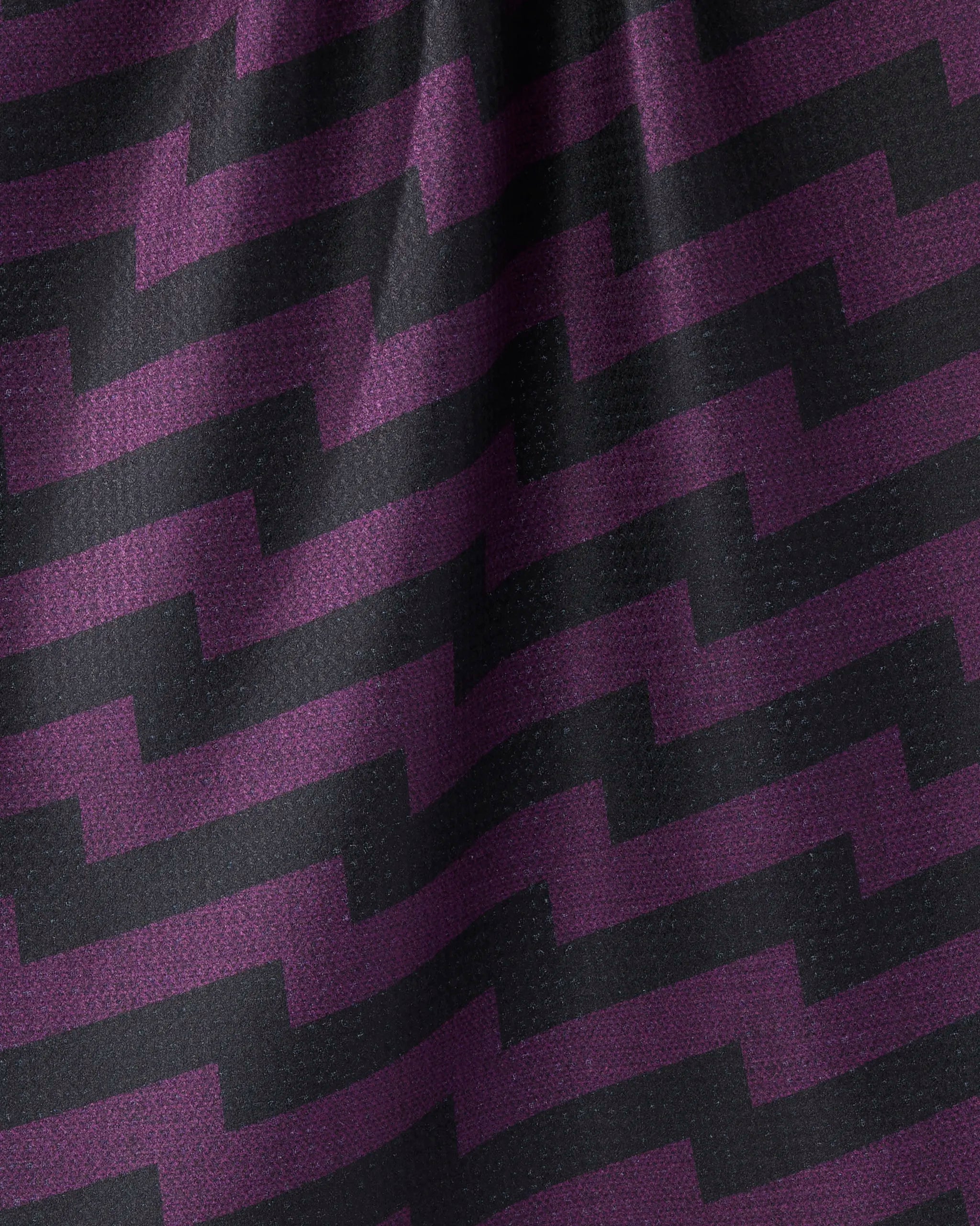 The Geometry Current tea towel features ultra-absorbent purple fabric with a black zigzag pattern, a slight wrinkle, textured finish, and subtle light reflections.