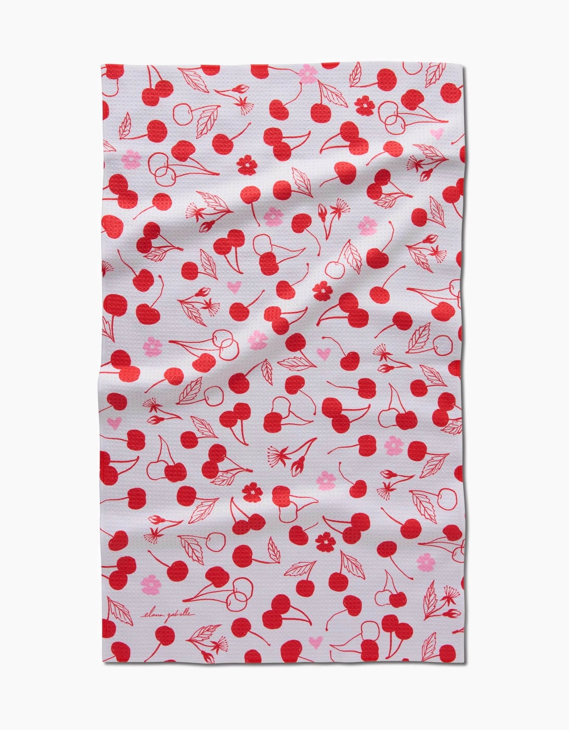 The Cute Cherry tea towel by Elana Gabrielle features a white textured fabric with a charming pattern of red cherries, leaves, and pink flowers. Slightly wrinkled for a cozy look, this absorbent towel adds sweet style to any kitchen.