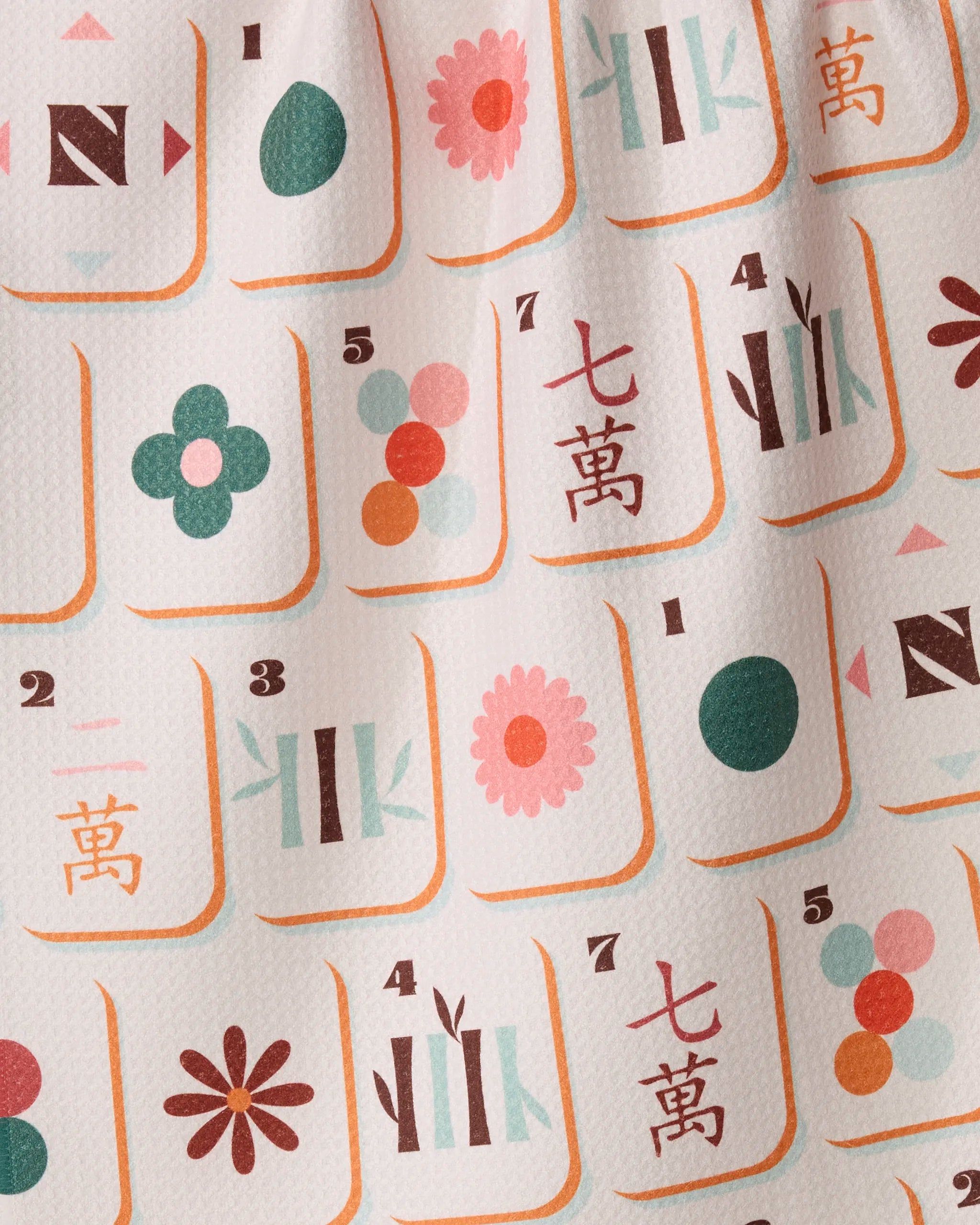 The Cypress Tile Toss kitchen towel by Geometry features vibrant symbols, numbers, and Chinese characters inspired by mahjong tiles, printed on textured white fabric made from recycled materials. With playful flowers, circles, and bamboo patterns in pink, green, orange, and teal hues, this ultra-absorbent tea towel is perfect for adding a unique touch to your kitchen.
