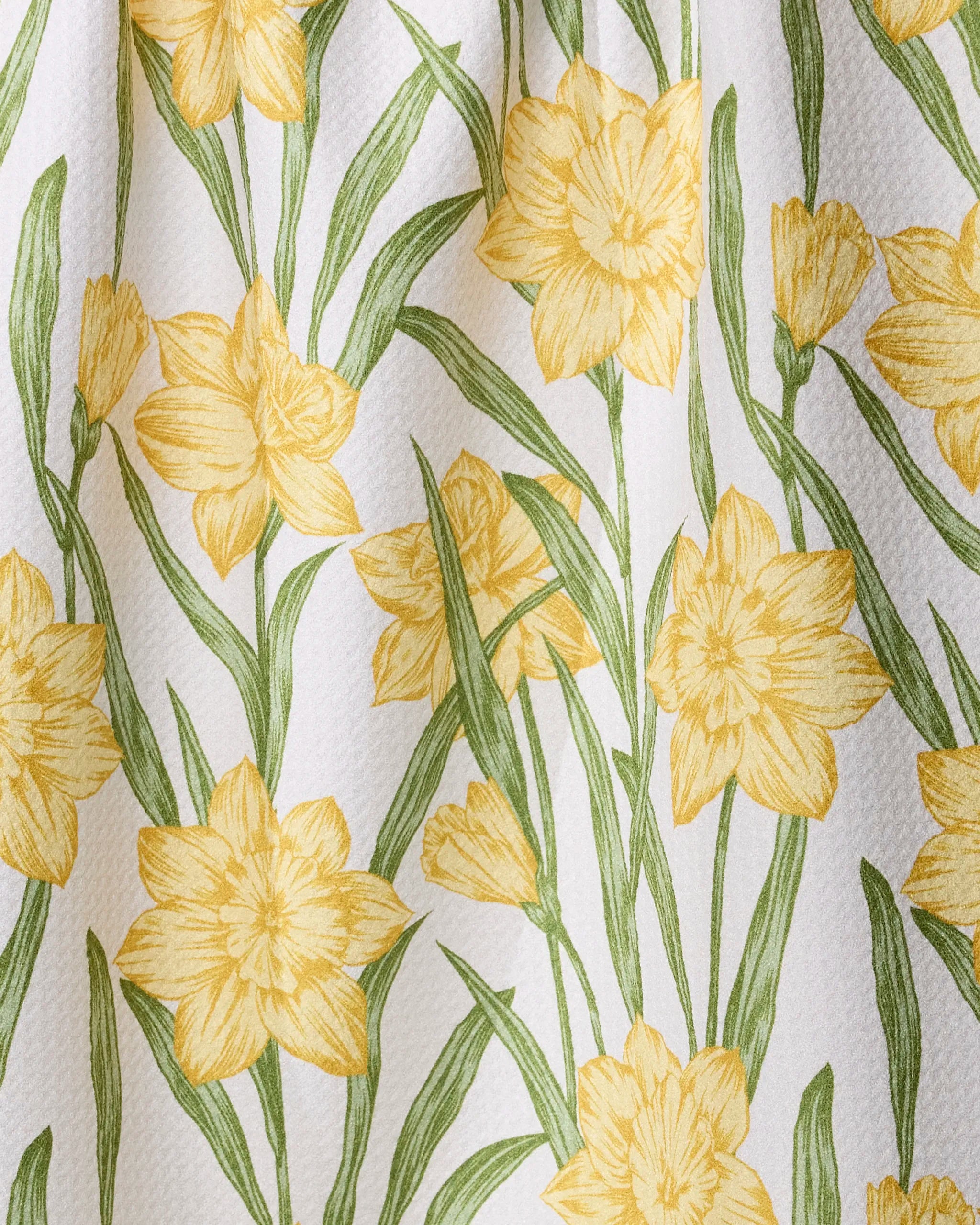 The Geometry Daffodil Darling quick-drying towel features a close-up of bright yellow daffodils and green leaves on white, giving the detailed floral design a fresh, spring-inspired look.