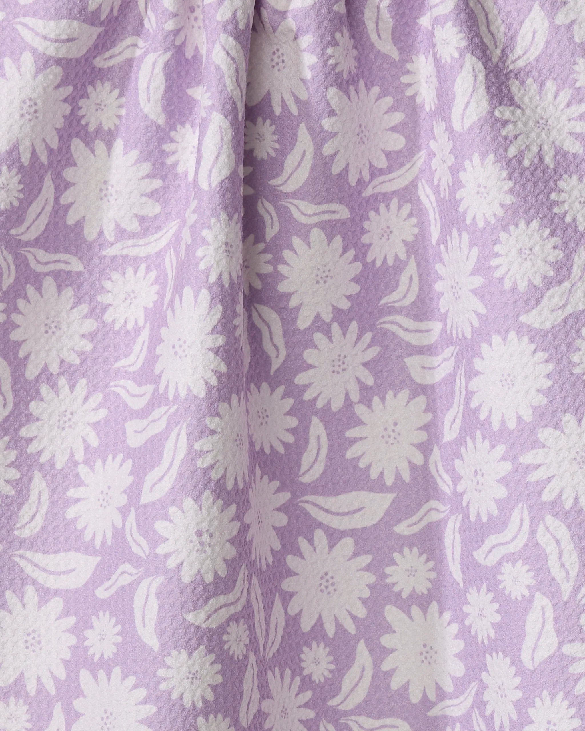 Close-up of the Kayla Ann Daisy Bloom ultra-absorbent towel, featuring a soft white floral and leaf pattern on a light purple background for a textured, gentle look.