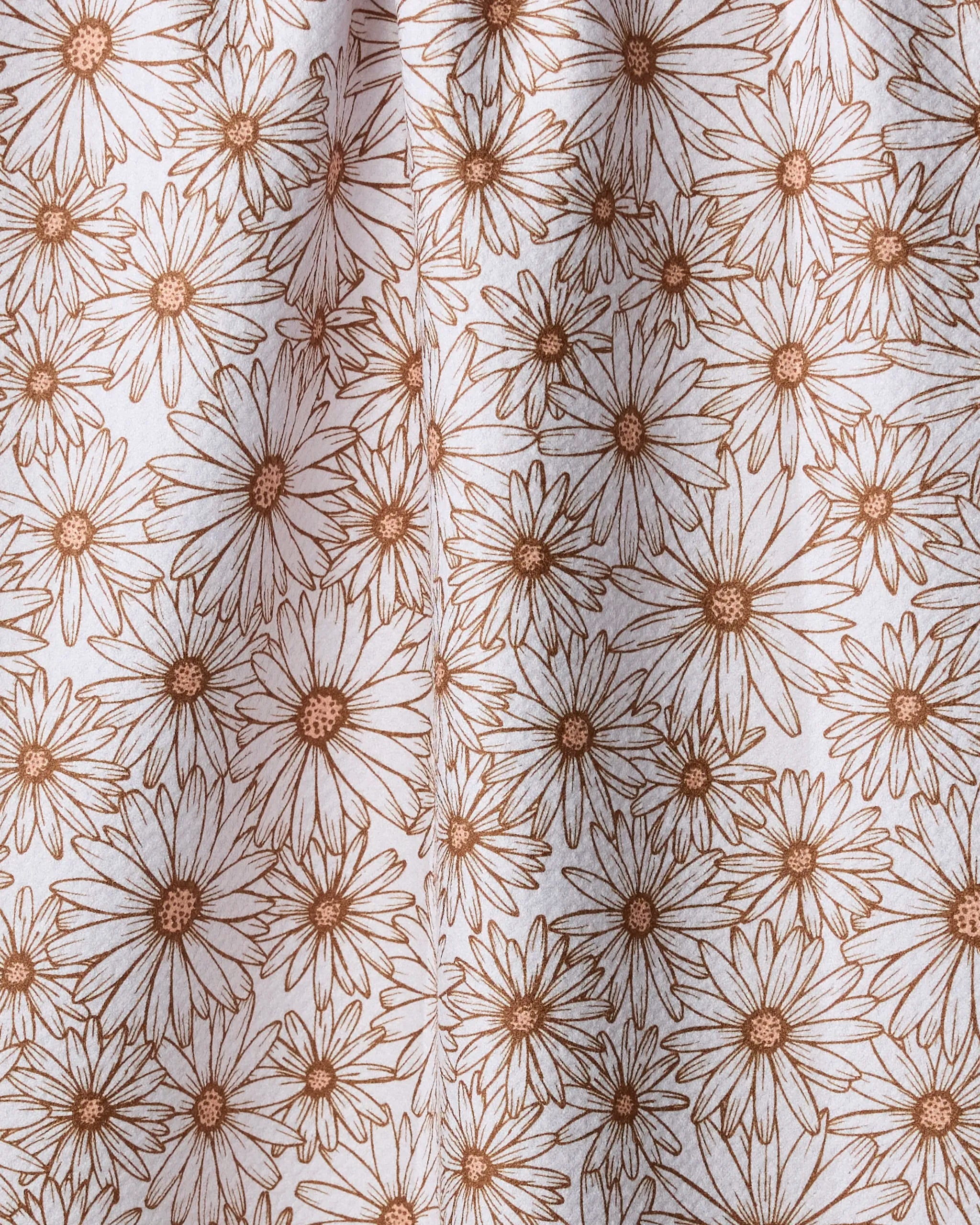 A close-up of Geometry's Daisy Trail tea towel, made from recycled materials and featuring a dense, repeating pattern of brown-outlined daisies on a white background.