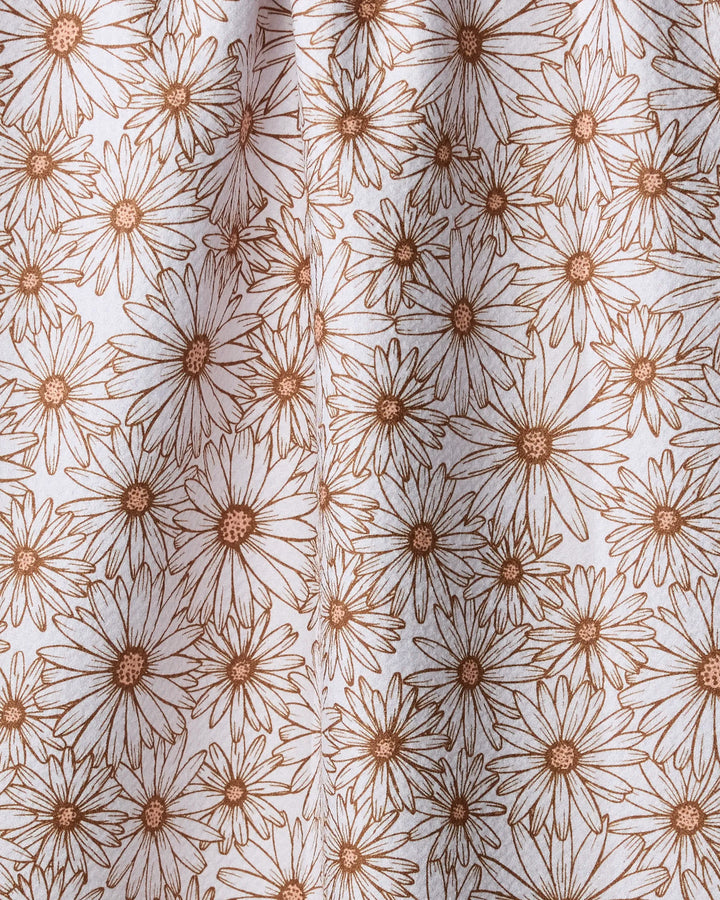 A close-up of Geometry's Daisy Trail tea towel, made from recycled materials and featuring a dense, repeating pattern of brown-outlined daisies on a white background.