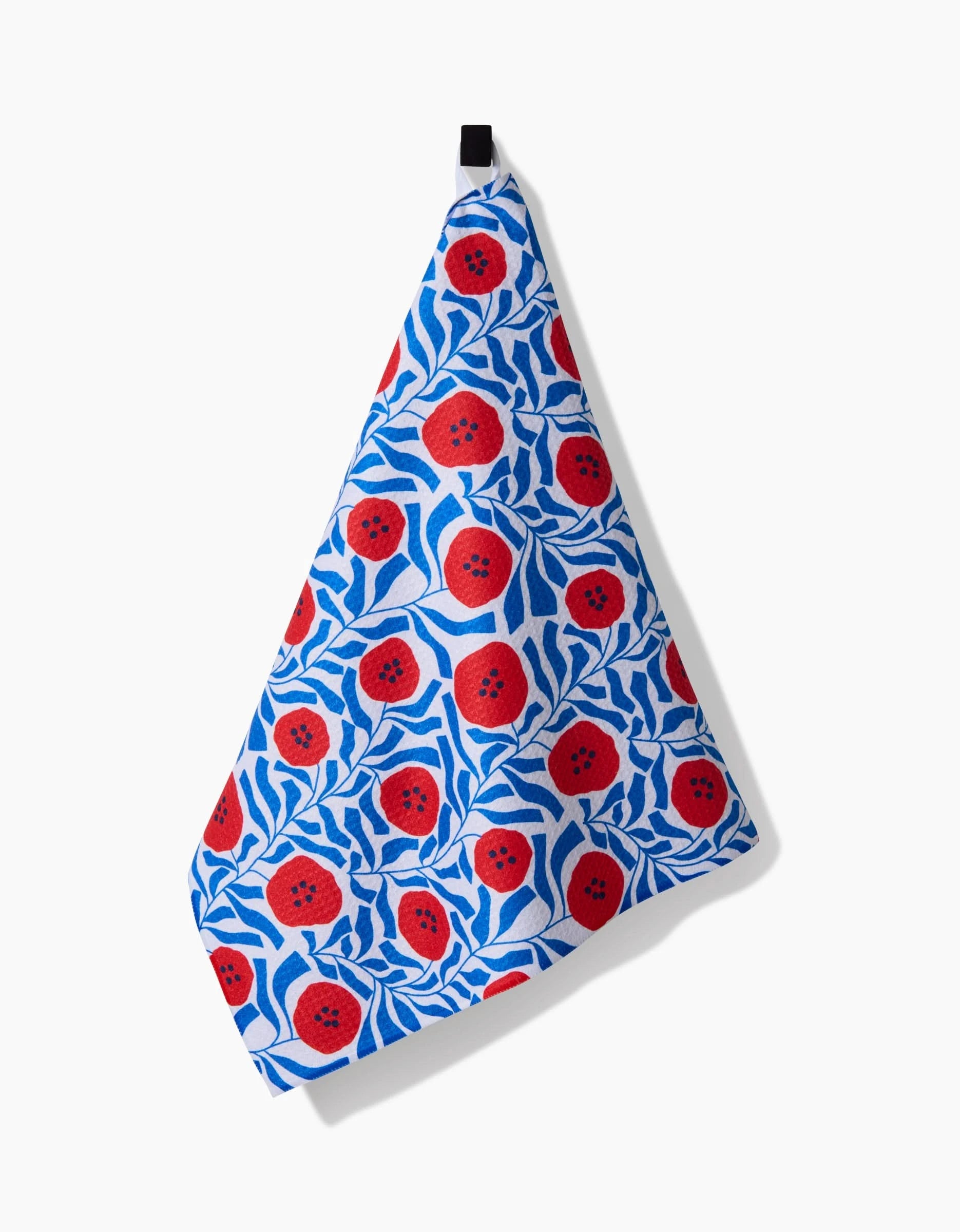 The Dancing Poppies towel by Happy Hemera features ultra-absorbent Geoweave fabric with a blue and white leafy pattern accented by bright red poppy shapes, hanging from a black loop against a white background.