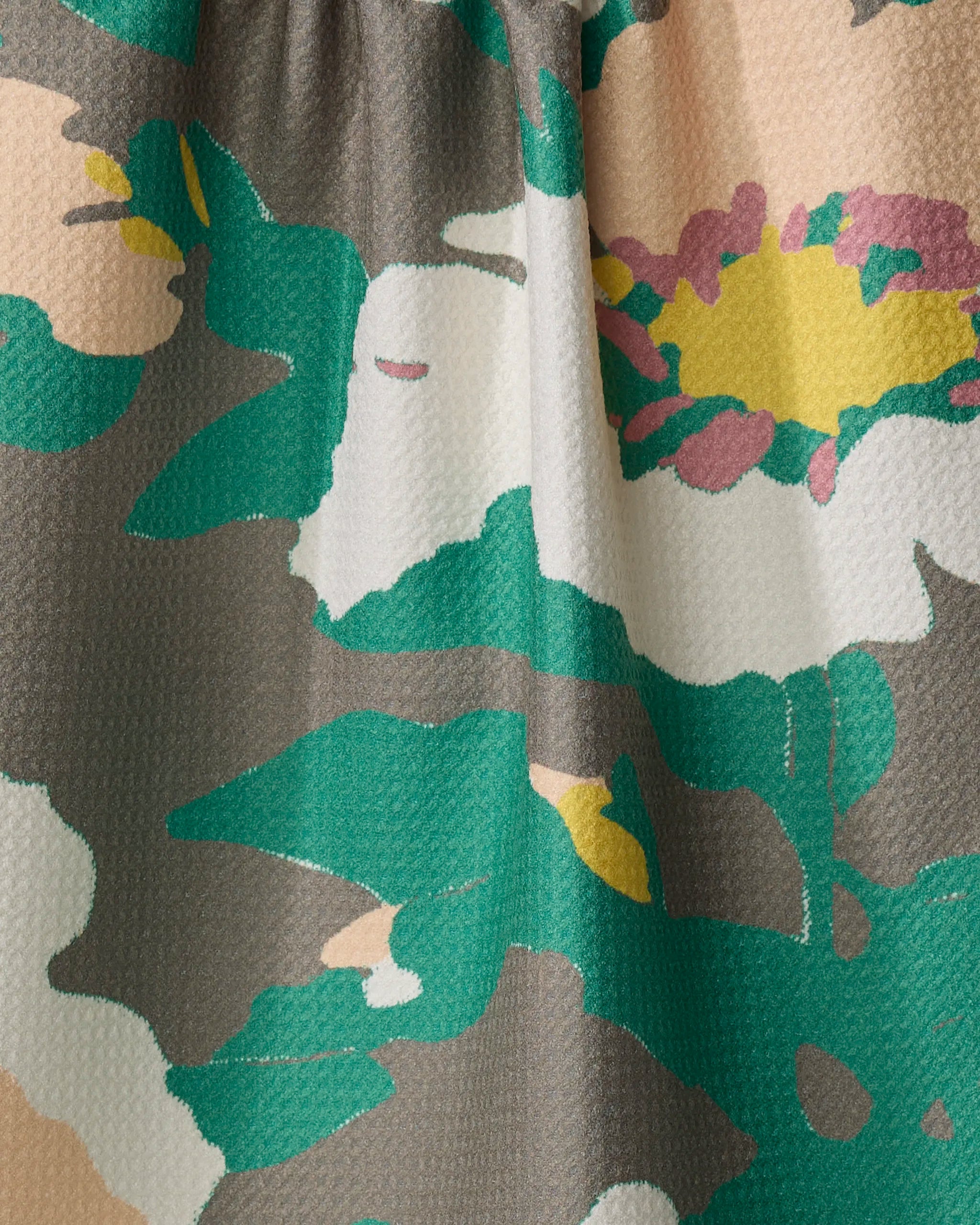 Close-up of the Darla tea towel by Geometry, made from quick-drying textured fabric with gathered seams and an abstract floral print in green, white, yellow, pink, and beige.