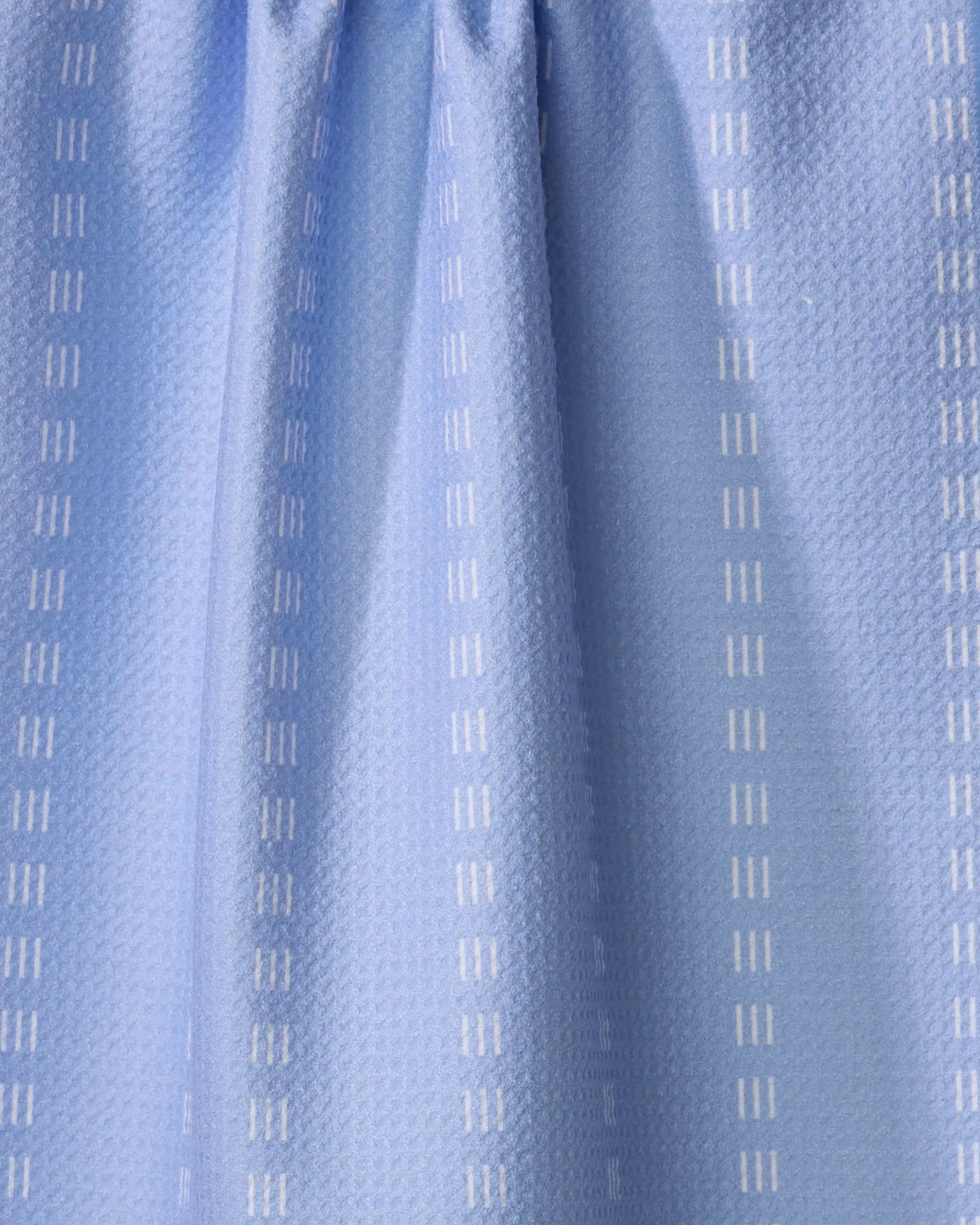 The Buy Guide's Dashing - French Blue kitchen towel is crafted from recycled materials, featuring a subtle textured pattern with vertical white dashed lines and soft pleats at the top.