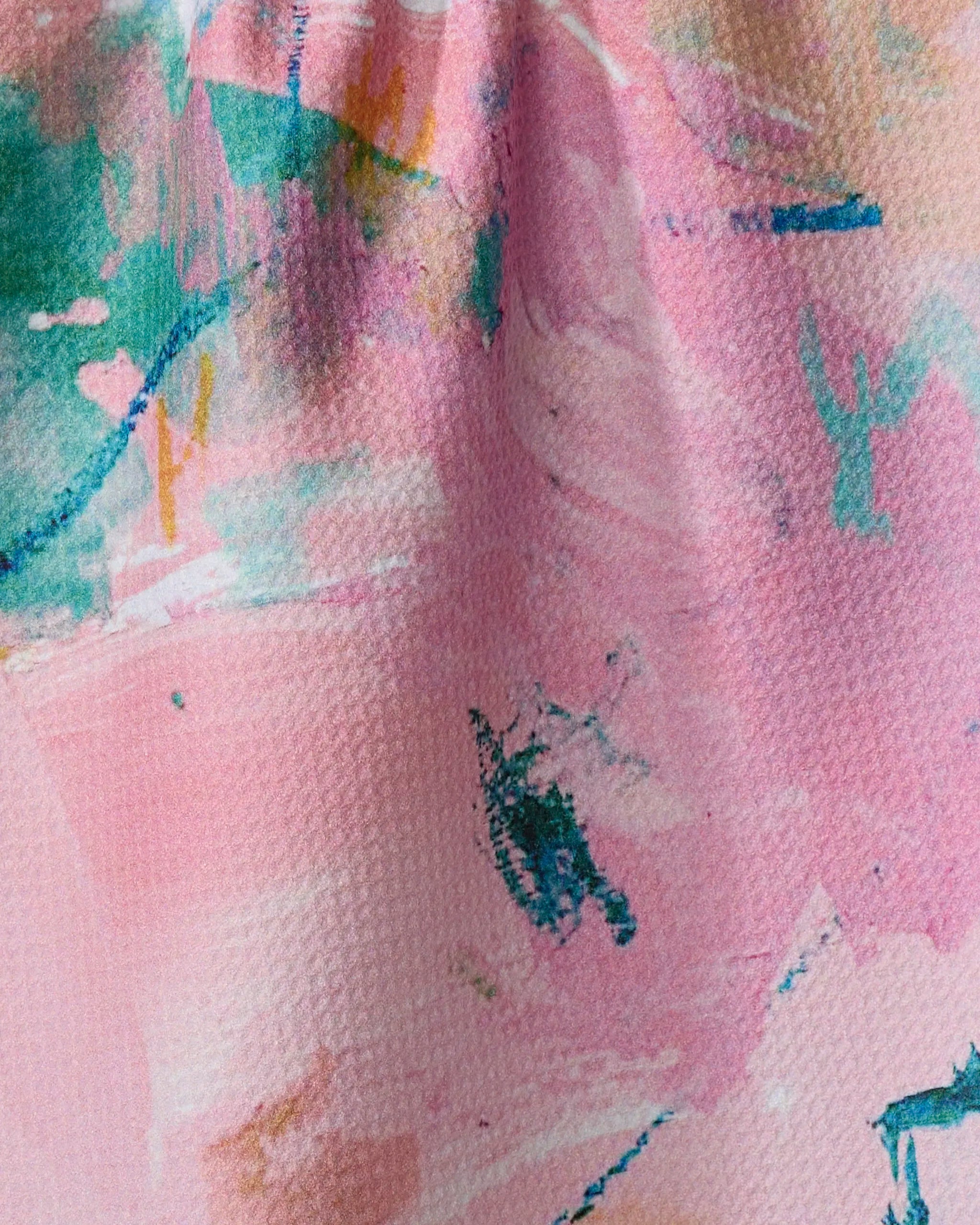 Close-up of "Daughter" tea towel by Sarah Holden: a colorful, artistic pattern with splashes of green, teal, and orange on pink, made from ultra-absorbent recycled materials.