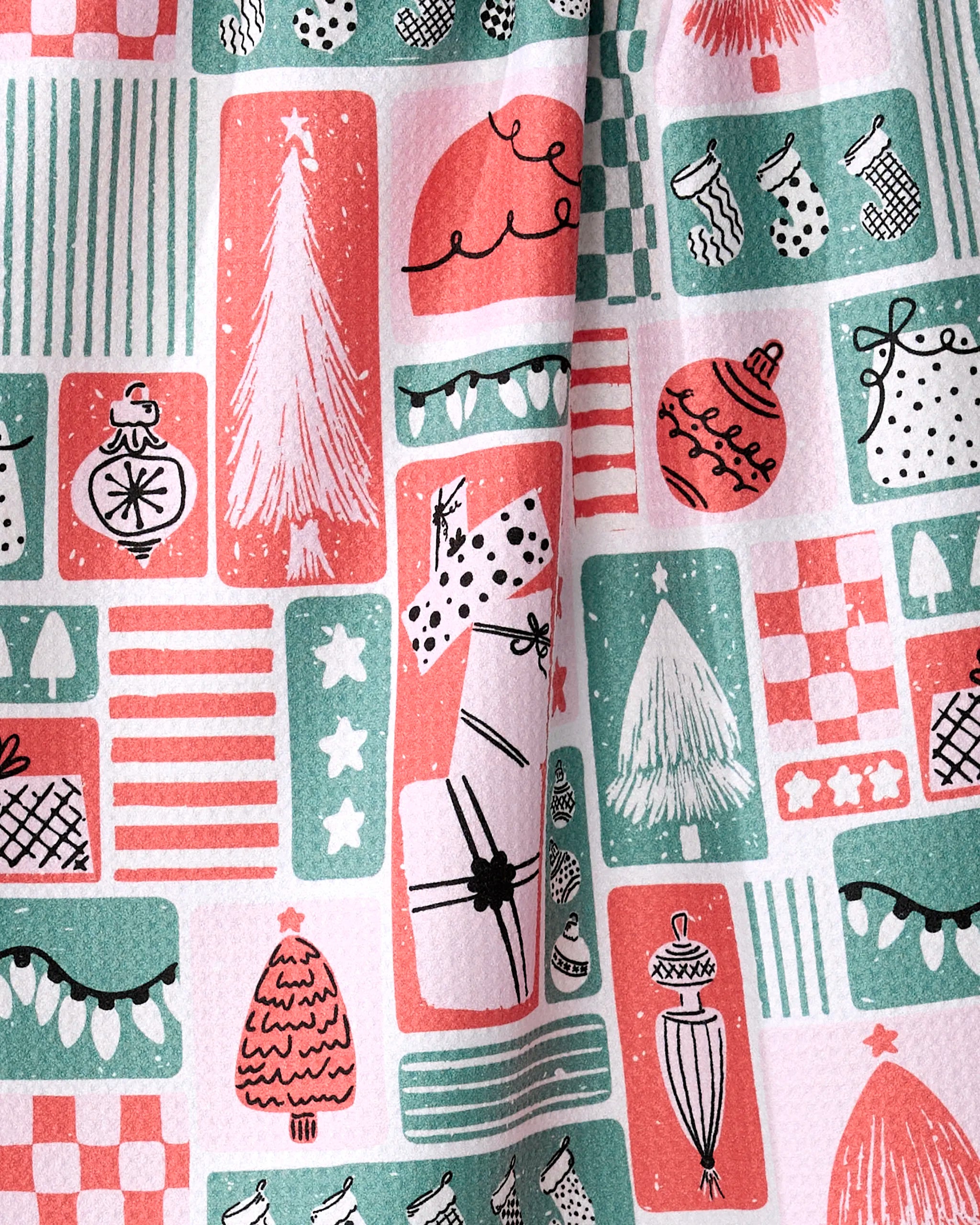 The Days of Christmas tea towel by Charlie Rowan Designs features festive red, green, and white holiday patterns—Christmas trees, ornaments, stockings, presents, polka dots, and stripes—made with recycled materials for a whimsical touch.