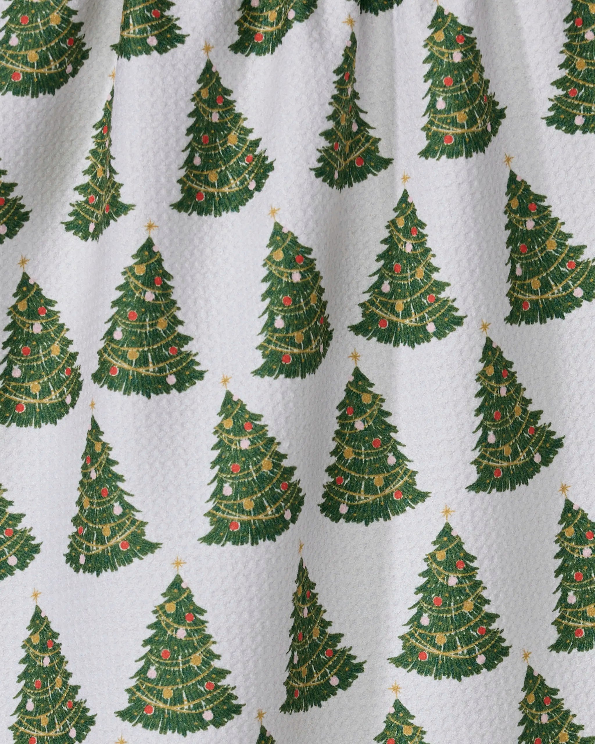 Geometry's Decked Out tea towel features a white textured design with evenly spaced Christmas trees adorned with ornaments and stars, arranged in neat rows. Made from quick-drying, recycled materials.