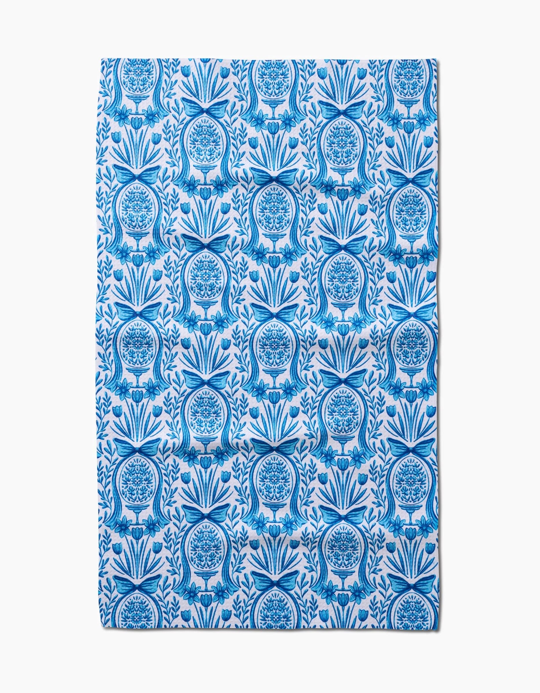 The Sarah Daugherty Delft Blue Easter Egg Damask tea towel features a repeating blue floral and fruit vase pattern with symmetrical, intricate detailing on a white background.