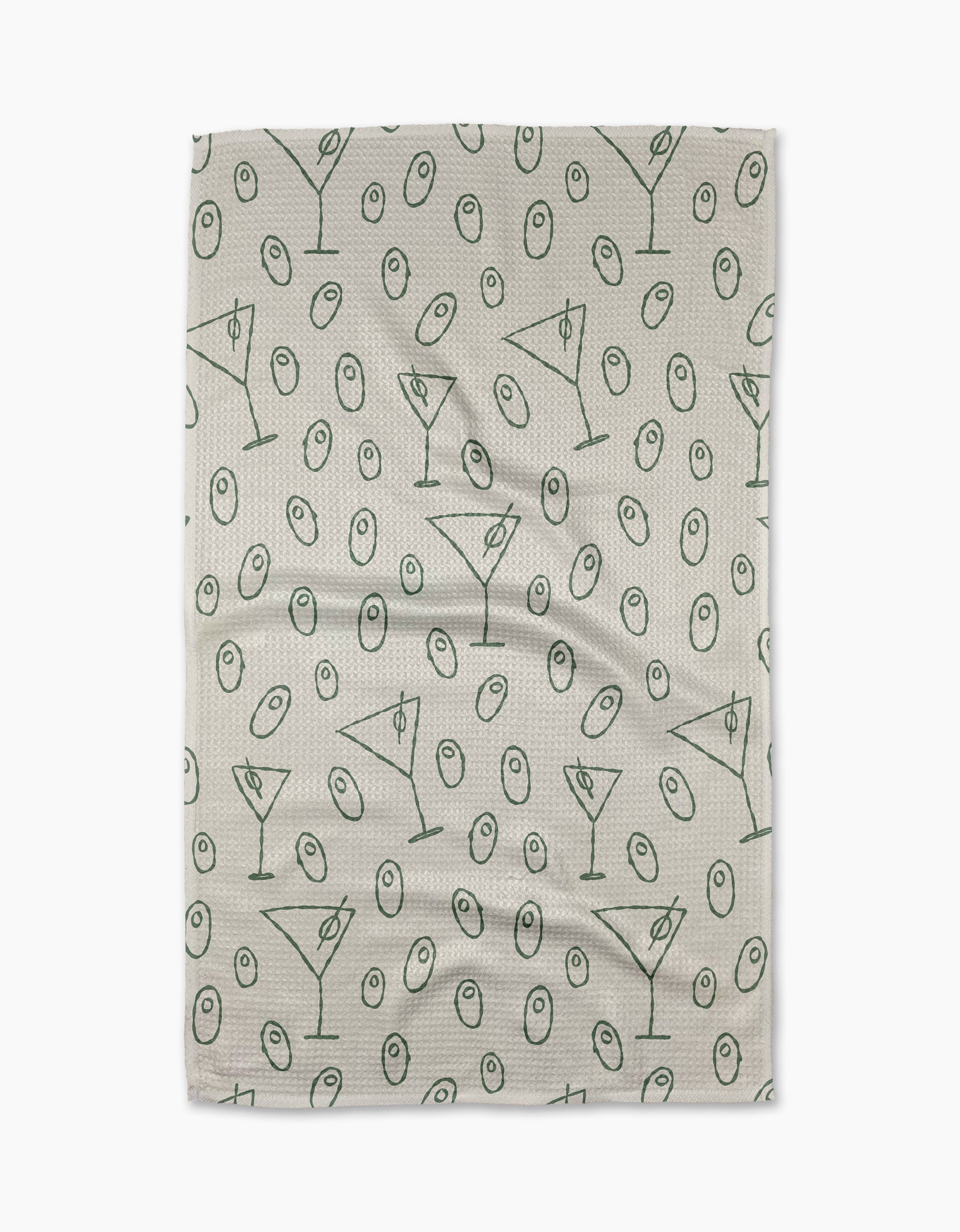 The Dirty Martini tea towel by Rosa Kichline showcases a beige textured background with a repeating pattern of green martini glasses and olives evenly scattered across the surface.