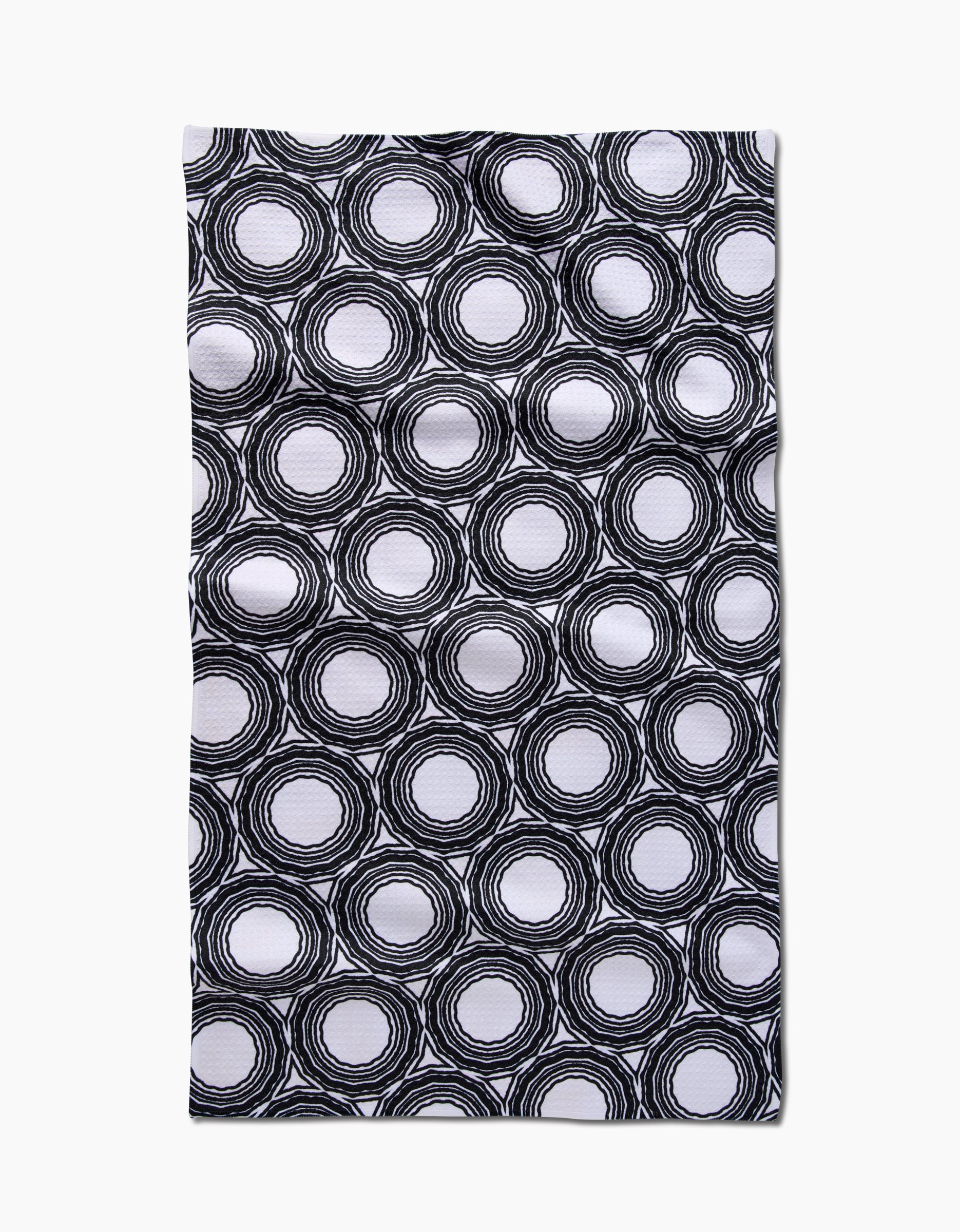 The Dosido tea towel by Katherine Berkeley features hand-drawn black concentric circles on white Geoweave fabric, creating a textured geometric look. Made from post-consumer recycled materials.