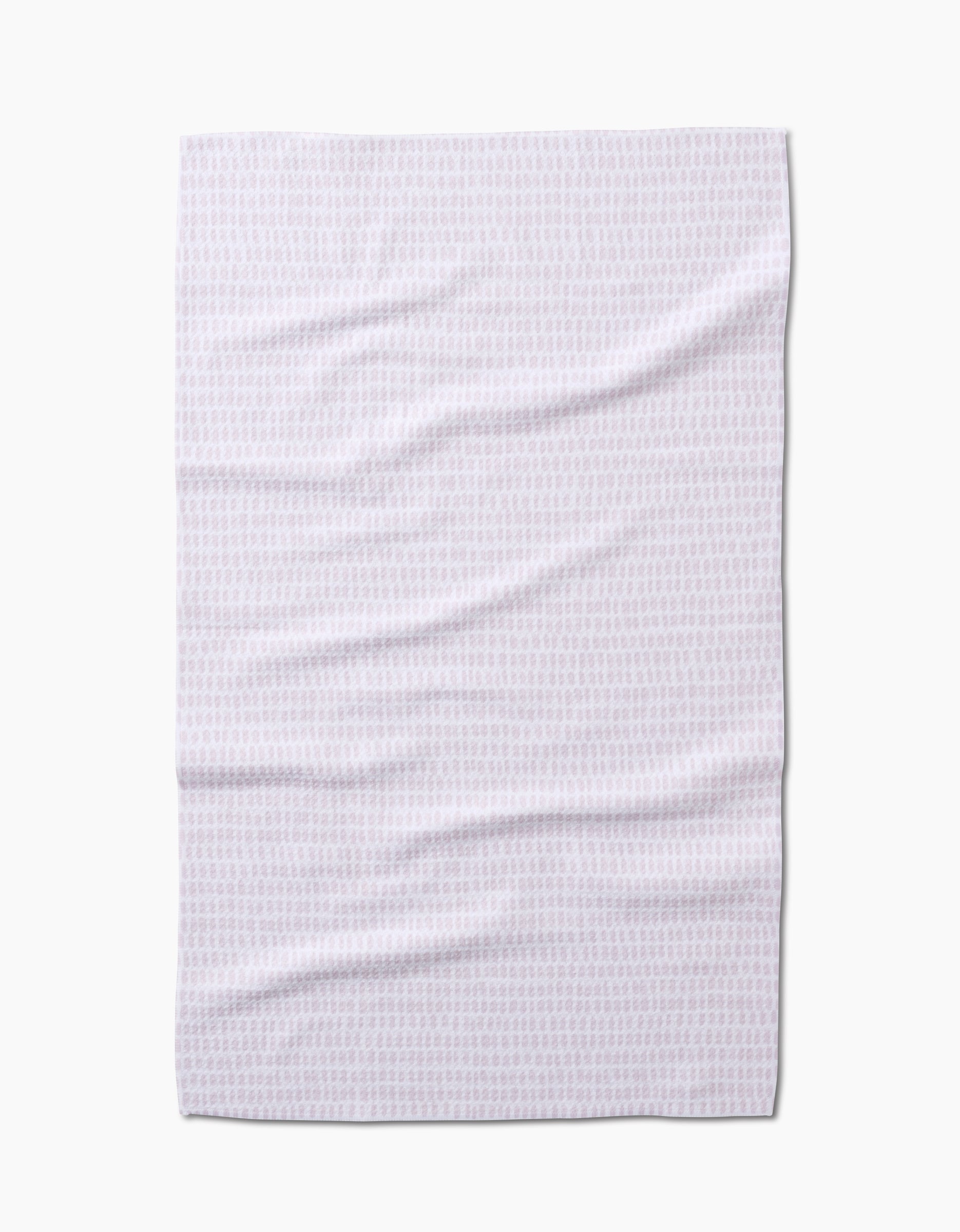 The Geometry Dot Dot Dot Blushed Bergamot is a white tea towel made from recycled materials, featuring a subtle light pink geometric pattern, shown flat and slightly wrinkled against a white background.