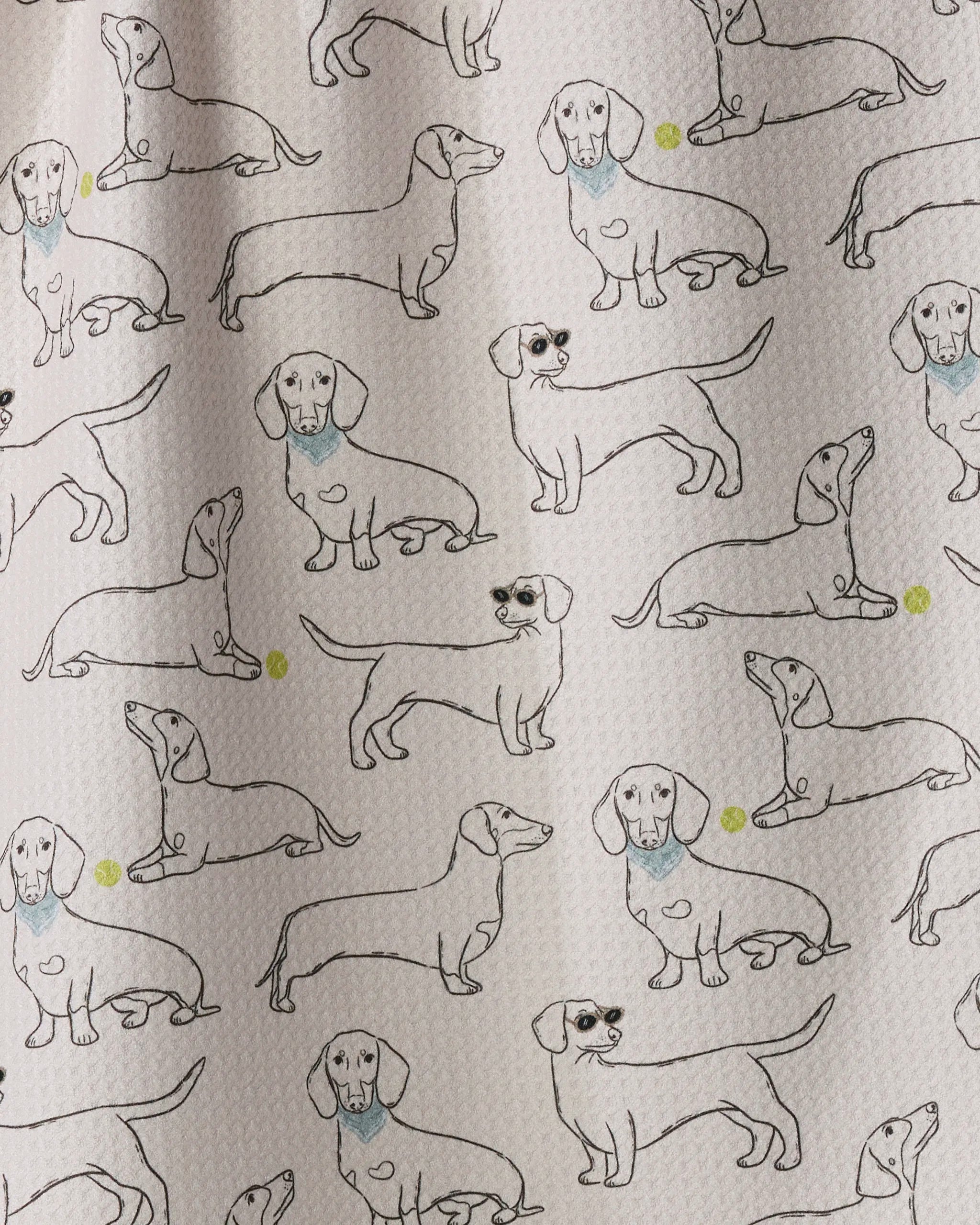 The “Doxie Pals” kitchen towel by Geometry features a playful, eco-friendly patterned fabric adorned with simple, repeated outline drawings of dachshund dogs—including some with blue-shaded necks—accented by cheerful yellow dots scattered between the illustrations.