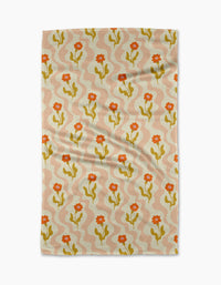 The Gerdadzy Dreamy Path dish towel features a rectangular, absorbent design with orange flowers, green stems, and light pink wavy lines on a beige background. The fabric has a slightly wrinkled appearance.