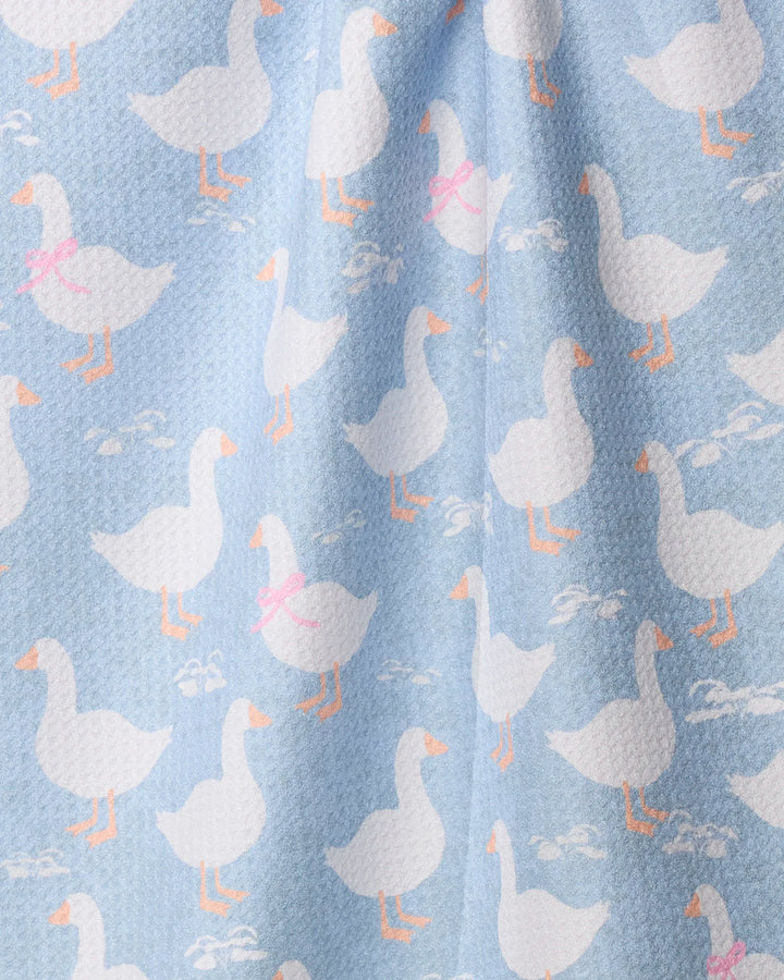 The Geometry Duck Trail tea towel features a light blue fabric with a repeating pattern of white geese—some wearing pink or blue bows—illustrated in playful walking poses. This quick-drying design combines charm and functionality.