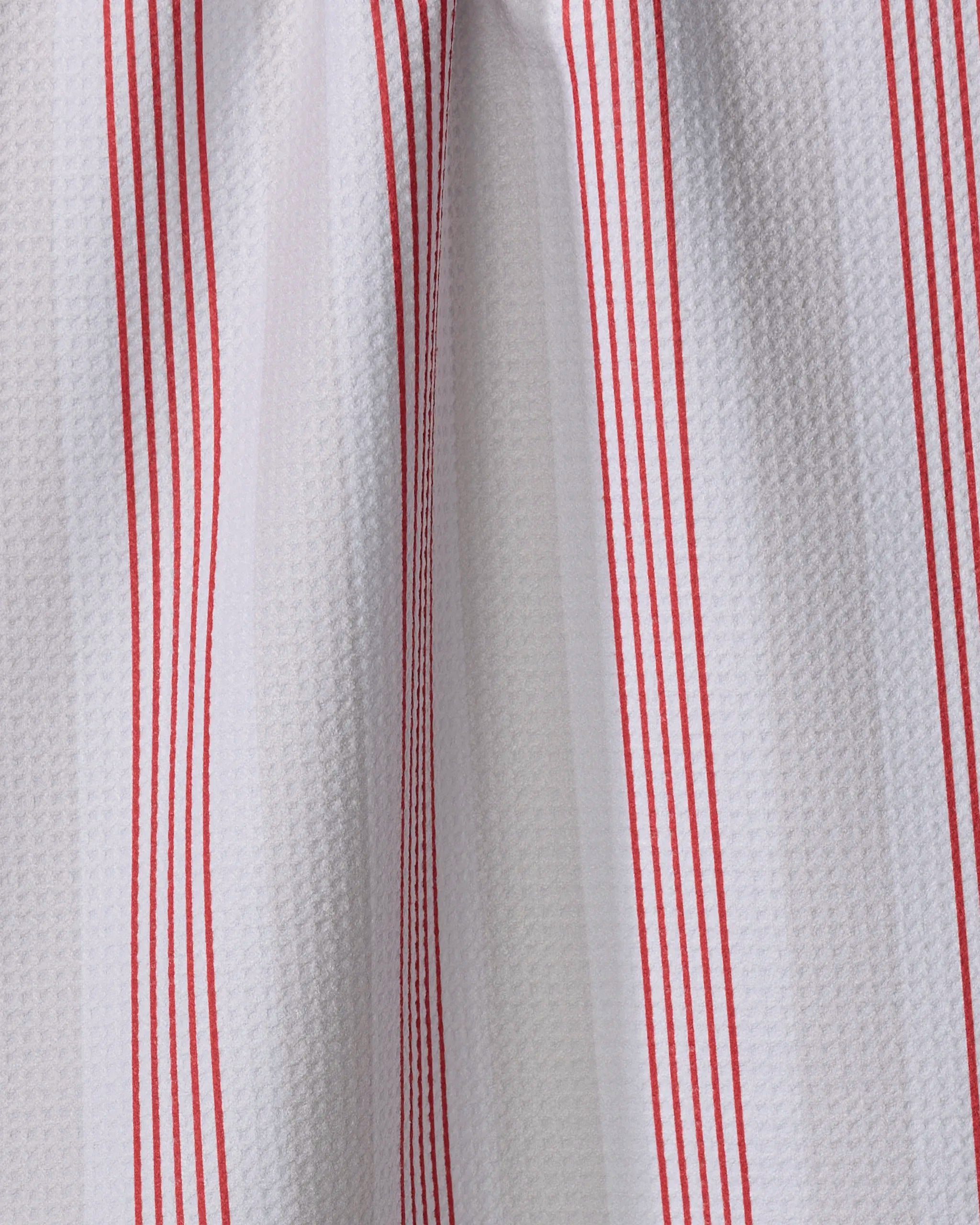 Close-up of "Earn Your Stripes - Candy Apple" by The Buy Guide: an ultra-absorbent white tea towel with textured fabric and evenly spaced vertical red stripes, draping in soft folds and casting subtle shadows.
