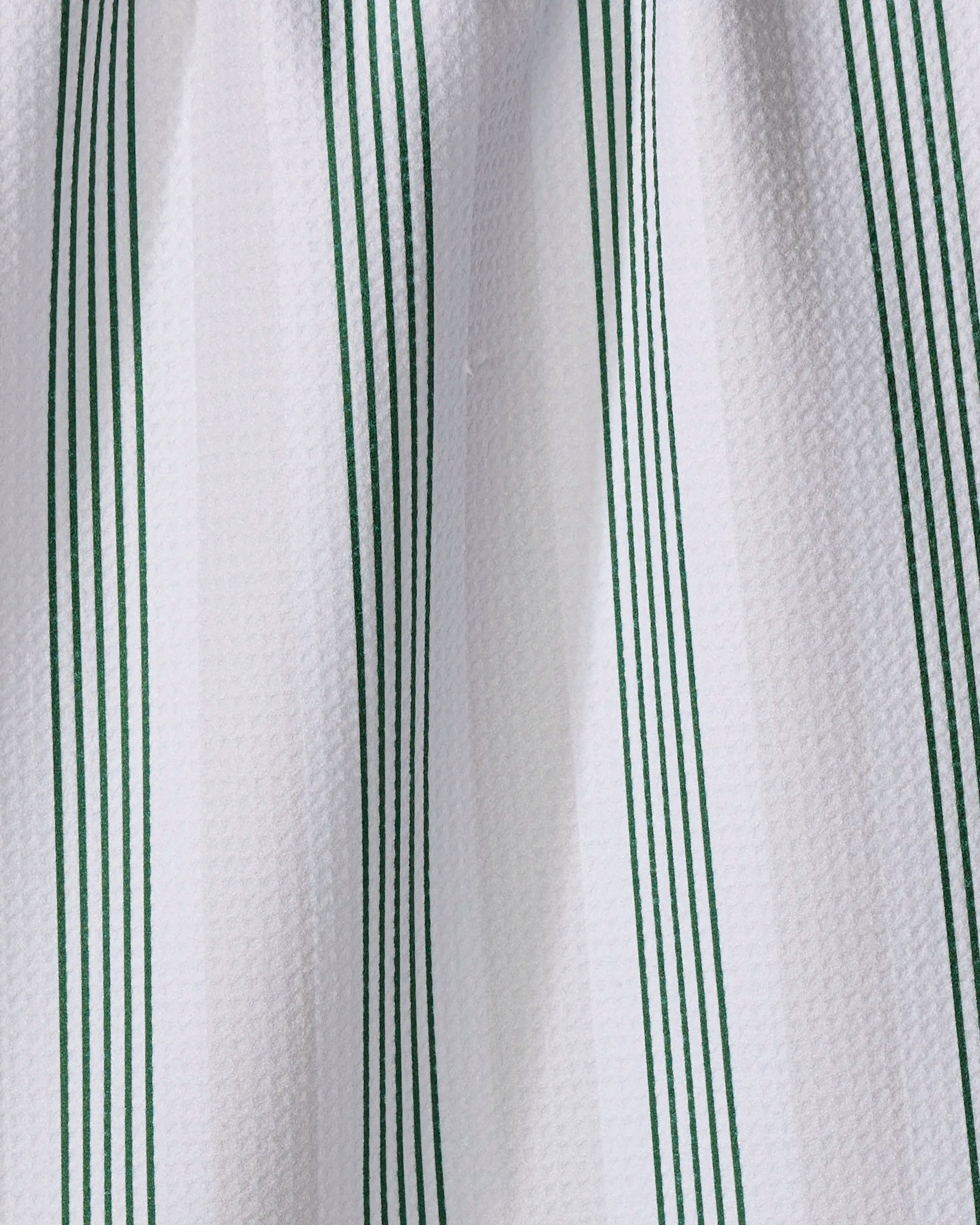 Close-up of The Buy Guide’s "Earn Your Stripes - Evergreen" tea towel, made from recycled materials, showcasing a white textured design with evenly spaced vertical green stripes in a repeating pattern.