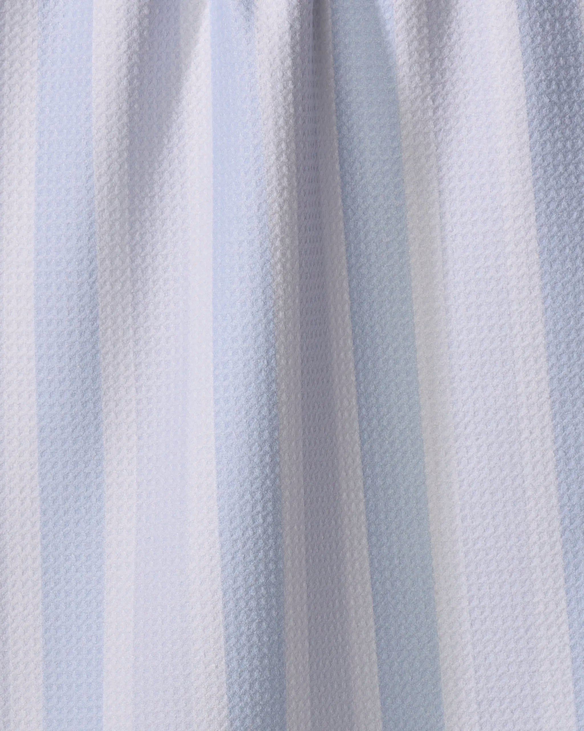 Close-up of The Buy Guide’s “Earn Your Stripes - Light Blue” tea towel, featuring light blue and white vertical stripes and a textured, waffle-like pattern, softly gathered at the top.