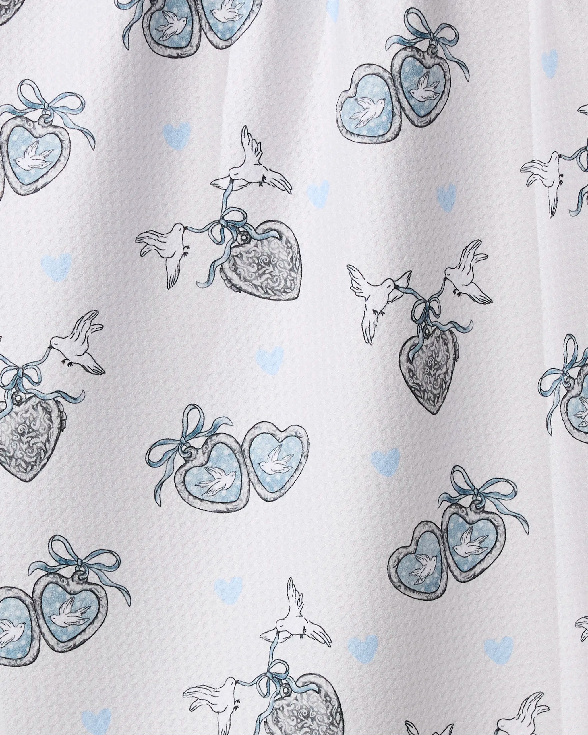 The Geometry "Easter Peace" eco-friendly tea towel features hand-drawn heart-shaped lockets, some with blue bows and doves, plus small blue hearts on a white background. Made from absorbent Geoweave fabric—perfect for your kitchen.