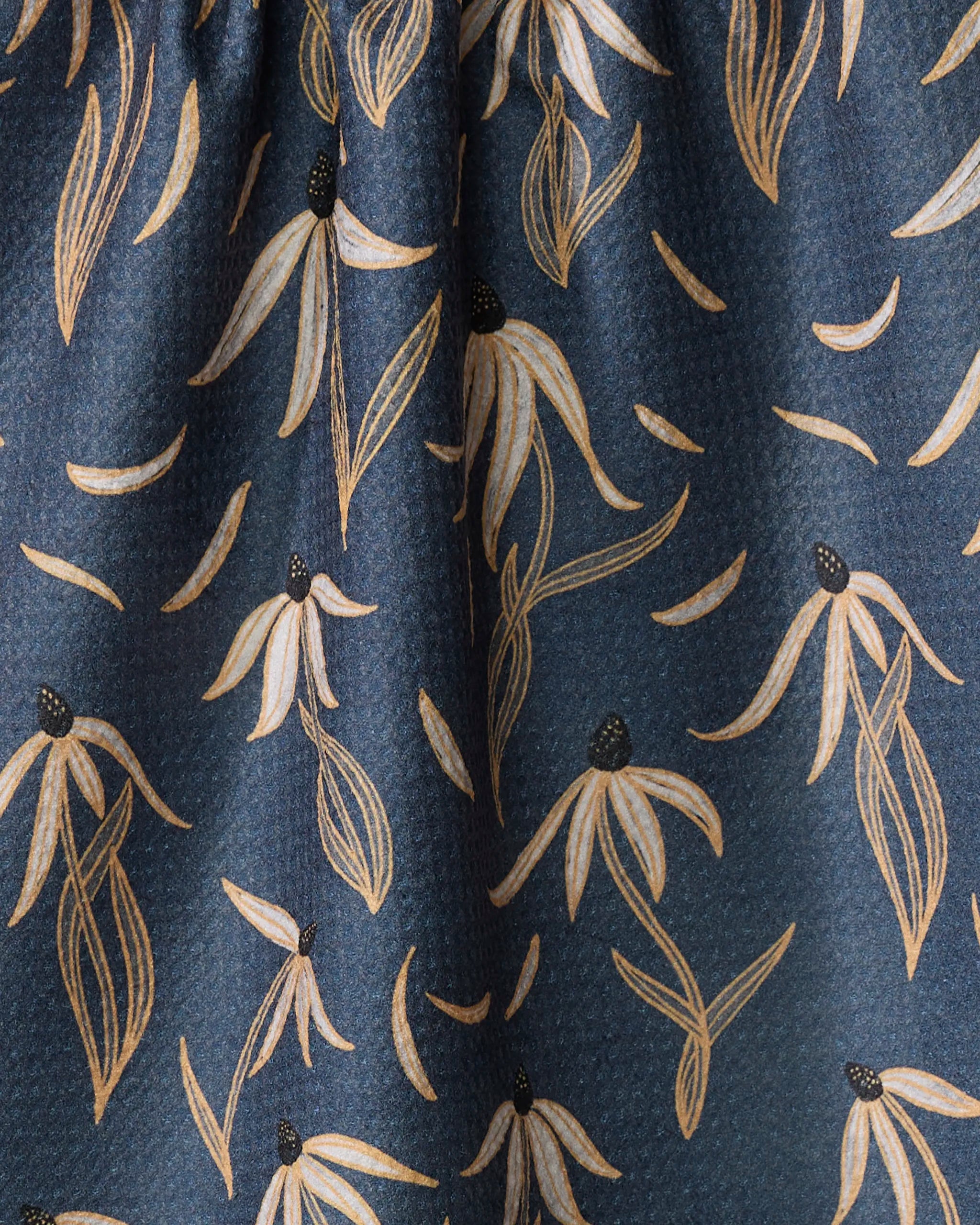 The Echinacea kitchen towel by Katie O'Shea features dark blue fabric with pale yellow stylized flowers and curved leaves in a geometric pattern, plus a slightly textured surface for added appeal.