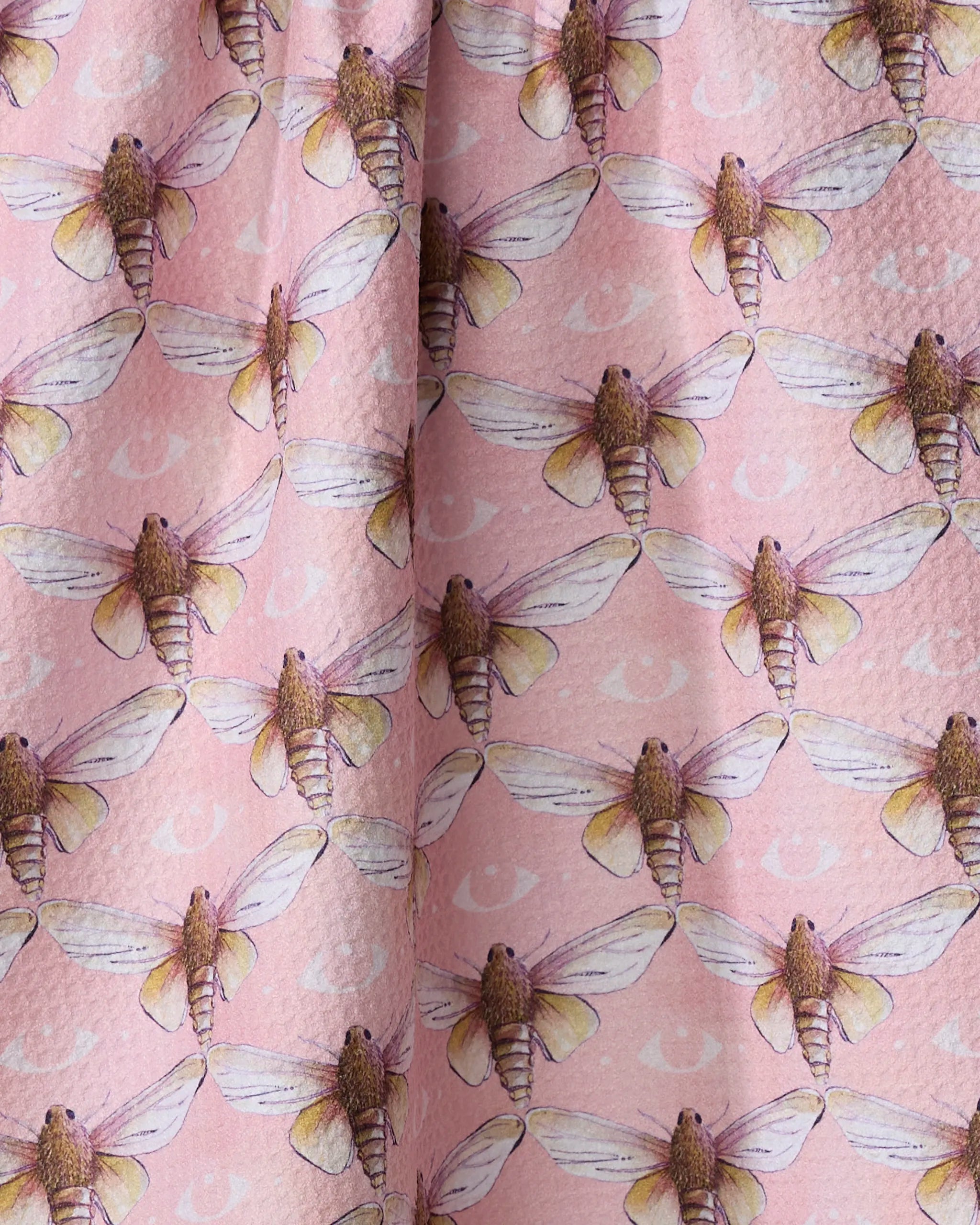 Echo by Maayan Alper-Swan: a pink Geoweave tea towel displaying detailed, realistic moths with outstretched wings and subtle crescent moon shapes in the background.