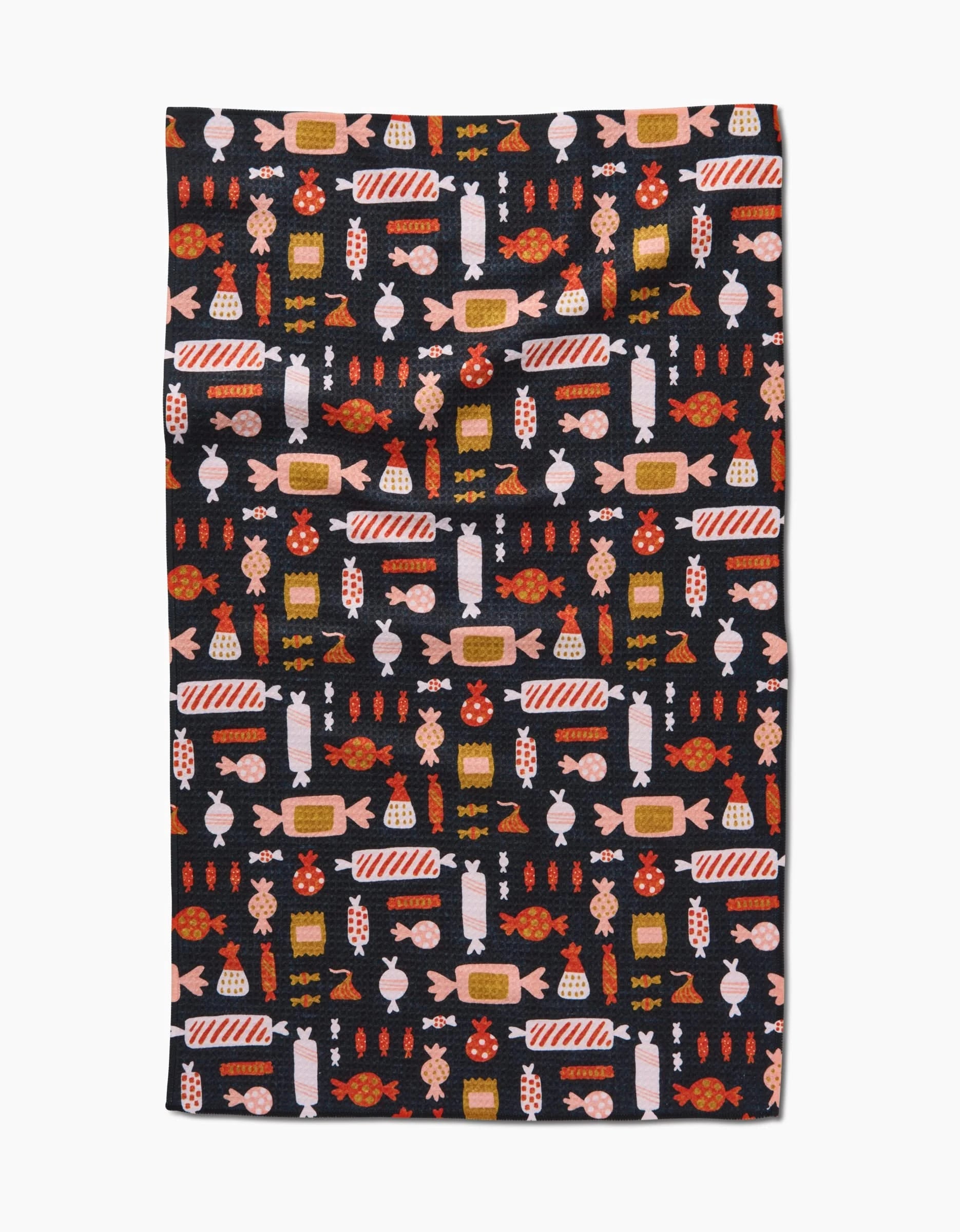 The Edwina tea towel by Amy MacCready is rectangular, made from recycled materials, and features a dark background with neatly arranged red, orange, pink, and white candy patterns in rows and columns.