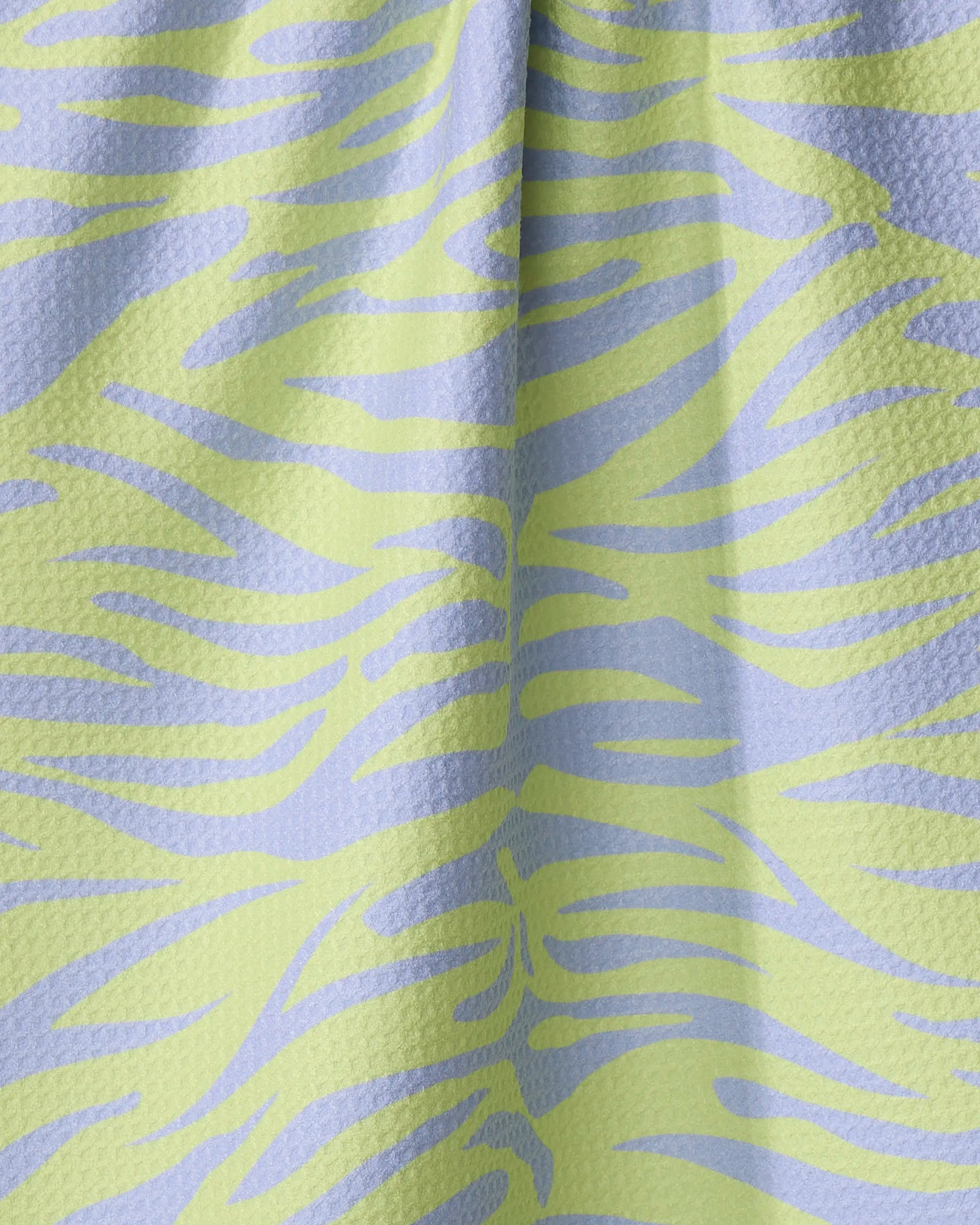 Close-up of Elisabeth Wing's Electric Tiger tea towel with a textured, wavy zebra-like pattern in pastel green and light blue. Made from quick-drying recycled materials, the fabric drapes softly in gentle vertical folds.