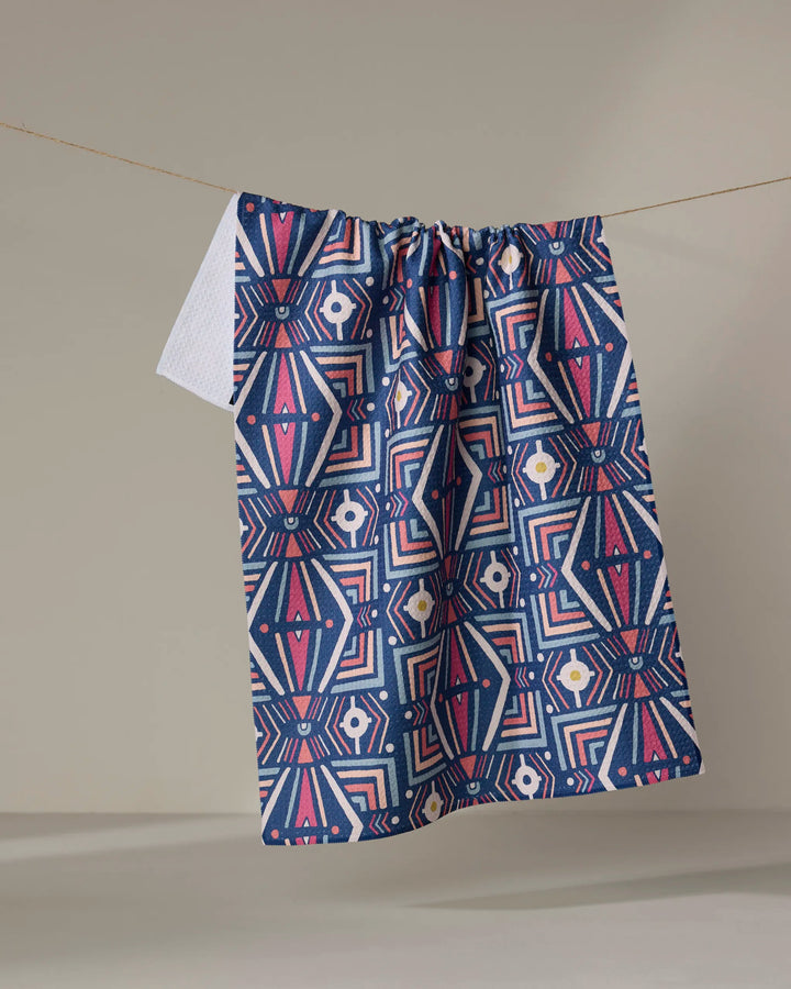 The Energetics tea towel by Jessica Swift features a geometric pattern in blue, pink, white, and yellow. Made from recycled materials, this ultra-absorbent kitchen towel offers sustainable style for your home.