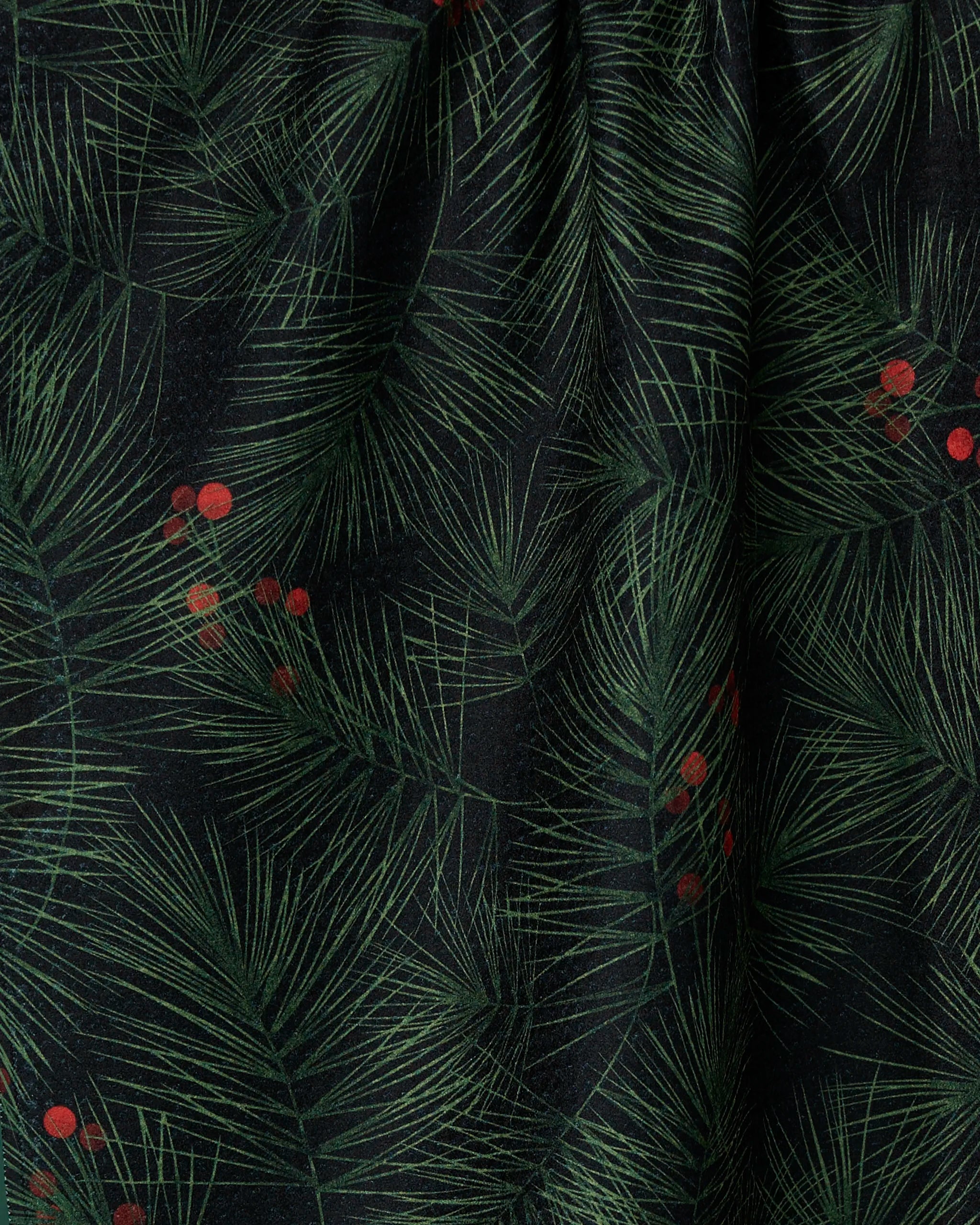 The Evergreen Pine tea towel by Geometry features a dark fabric with green pine needles and red berries for a festive, nature-inspired look. Made from recycled materials, it has a slightly gathered texture for added visual appeal.