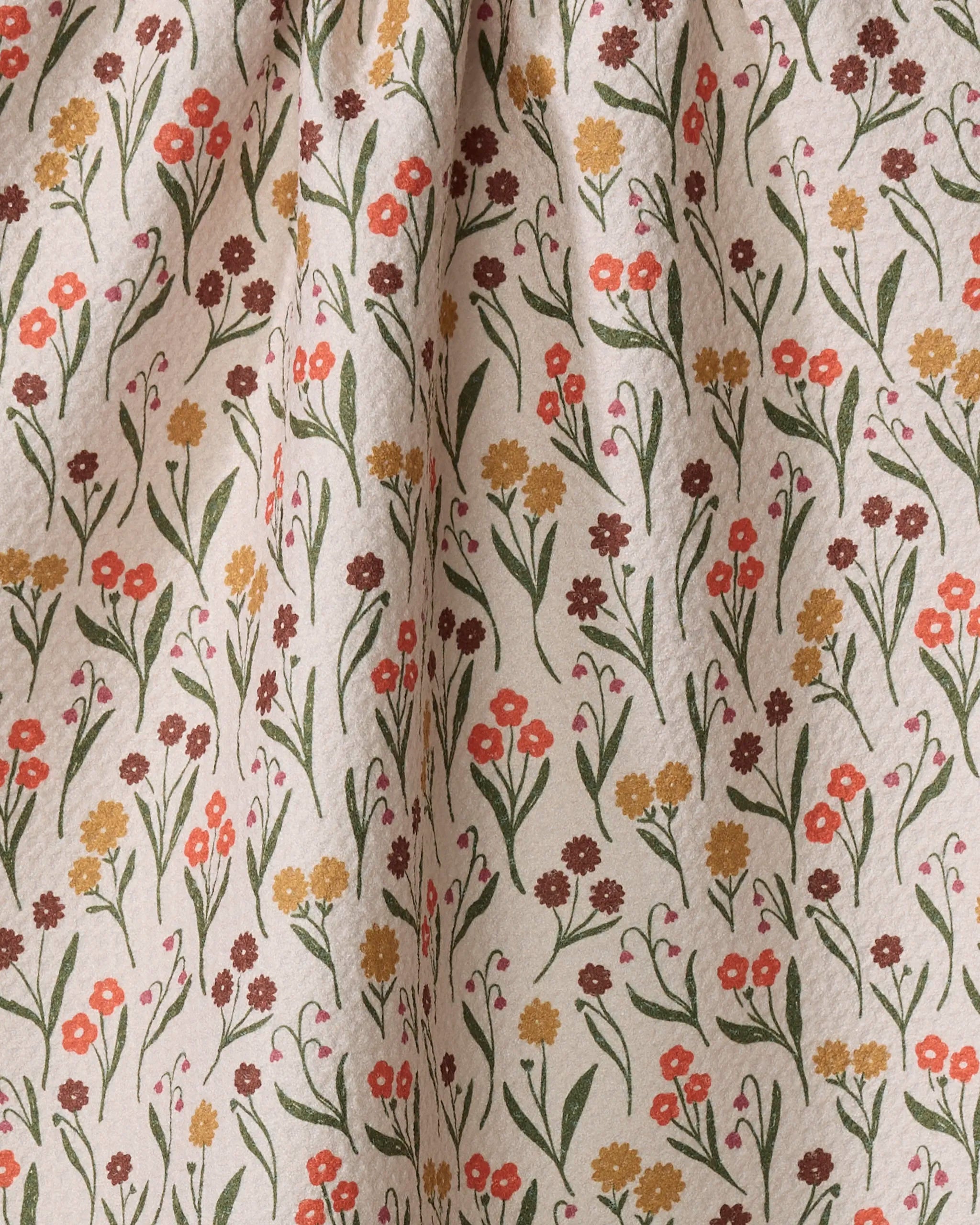 The Kayla Ann Fall Blossom kitchen towel features a cream color and floral pattern with red, yellow, and brown flowers plus green leaves. Its softly gathered fabric adds gentle folds and charming style to your kitchen.