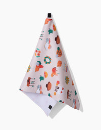 The Fall Favorites tea towel by Ceyda Alasar features colorful food and drink illustrations on light pink. Hanging from a black loop, it adds style and practicality to your kitchen with its quick-drying fabric.