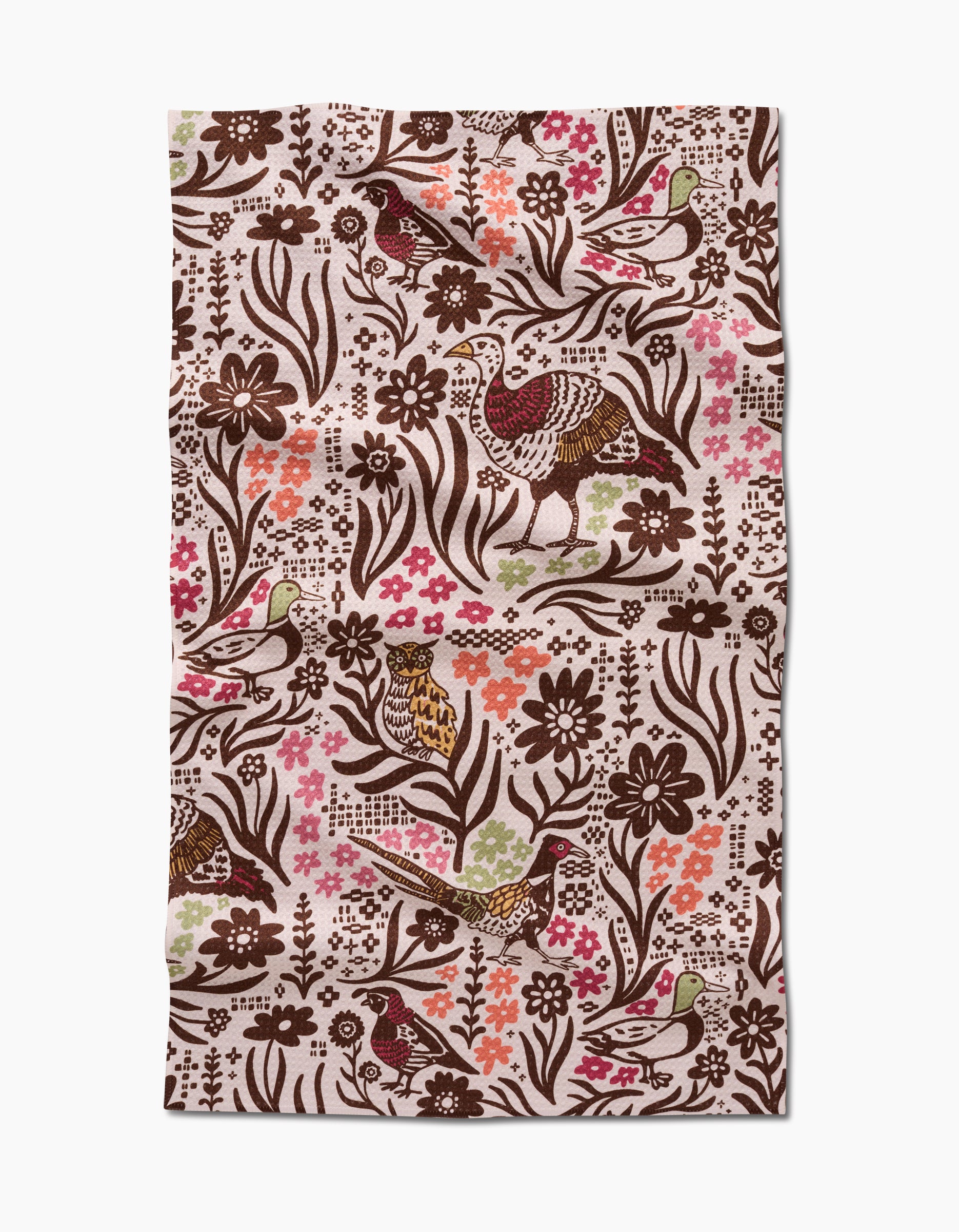 The Kayla Ann Fall Fowl tea towel is rectangular and made from recycled materials, featuring a floral and bird pattern in brown, green, and pink on a cream background. The fabric has a slightly wrinkled texture.