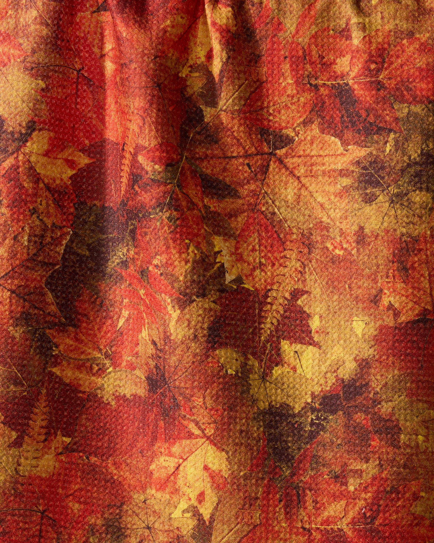 The Geometry Falling Foliage tea towel showcases a textured design with overlapping red, orange, and yellow leaves for a warm, autumn-inspired look.
