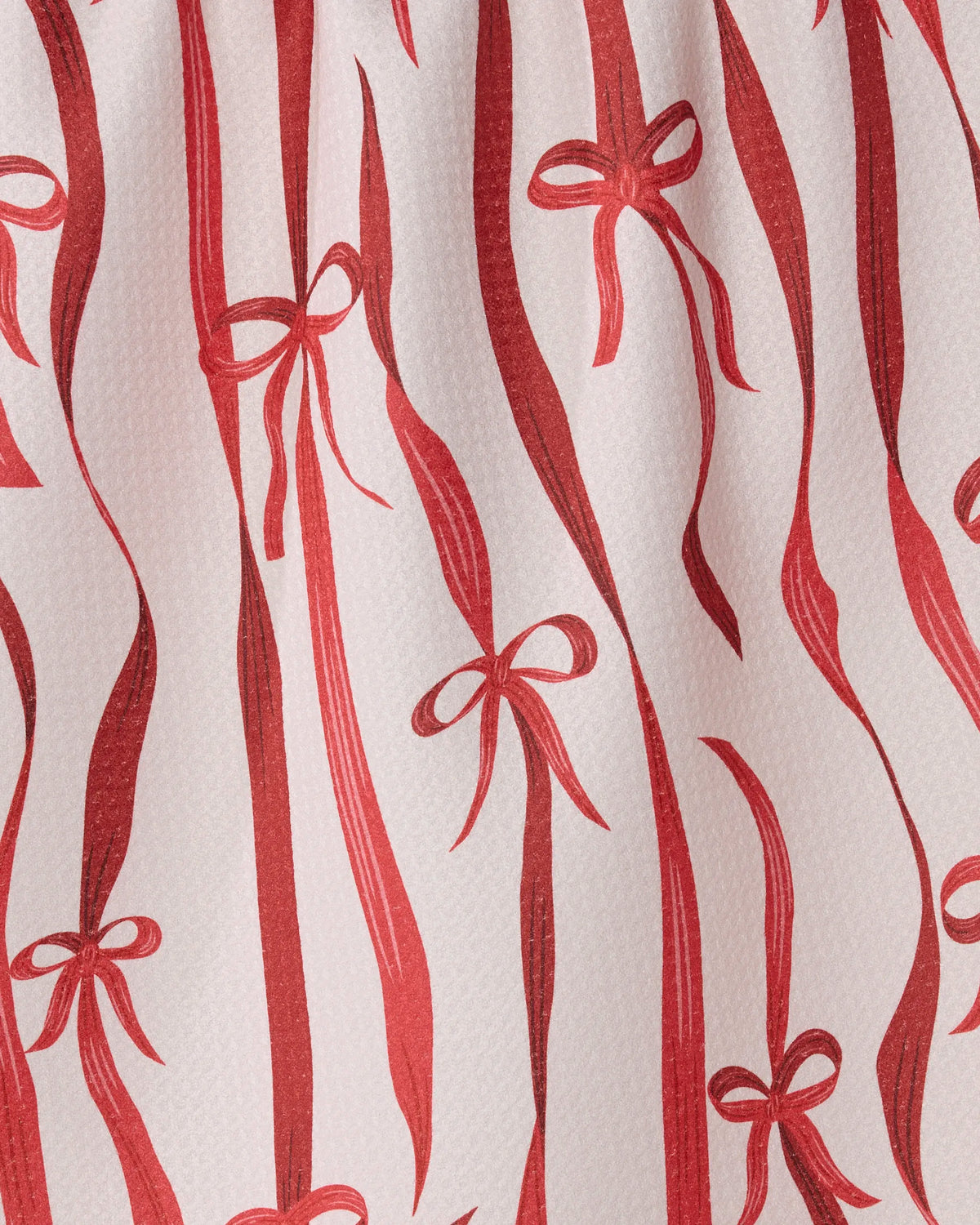 Featuring Geometry’s Falling Ribbon design, this ultra-absorbent tea towel showcases festive red ribbon and bow patterns on a white textured background, with alternating thick and thin stripes and various bow shapes scattered throughout. Crafted from recycled materials, the Falling Ribbon kitchen tea towel combines eco-friendly charm with stylish elegance—making it a practical and eye-catching addition to any kitchen.