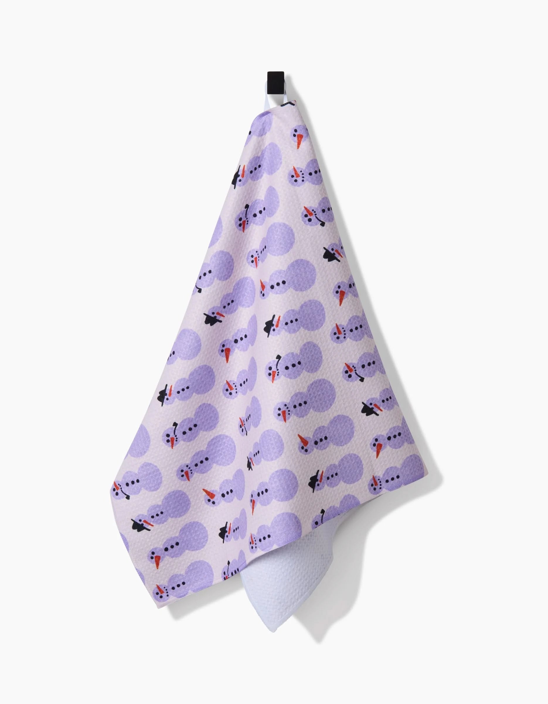 The Felicity Purple tea towel by Amy MacCready, made from recycled materials, displays purple clouds, black cats, and red-and-white fish on lavender fabric and hangs from a black loop against a white background.