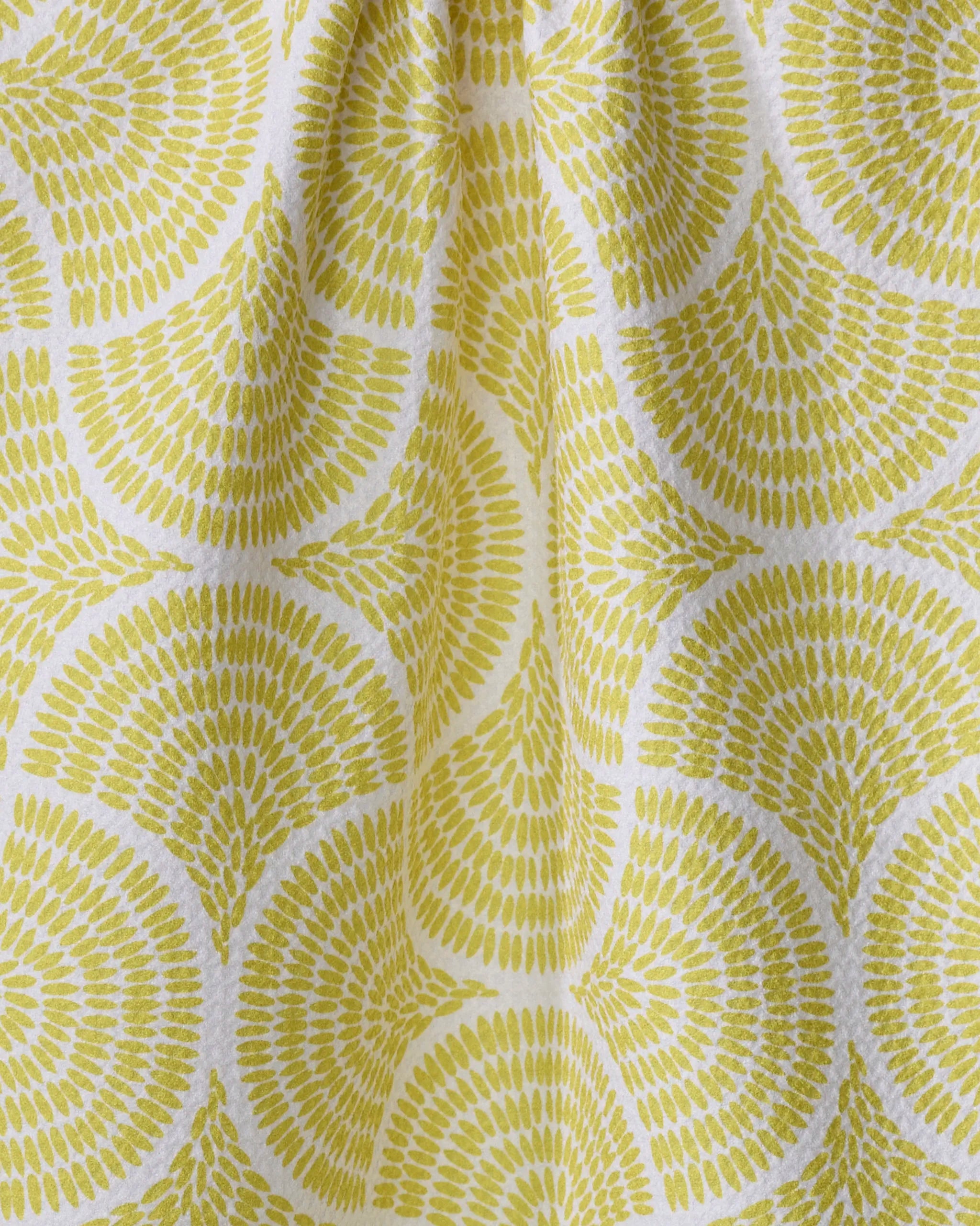 The "Ferns" recycled kitchen towel by Dabney Lee features yellow and white fan patterns with a textured, radial look. Gentle folds at the top add style, making it a chic addition to your space.