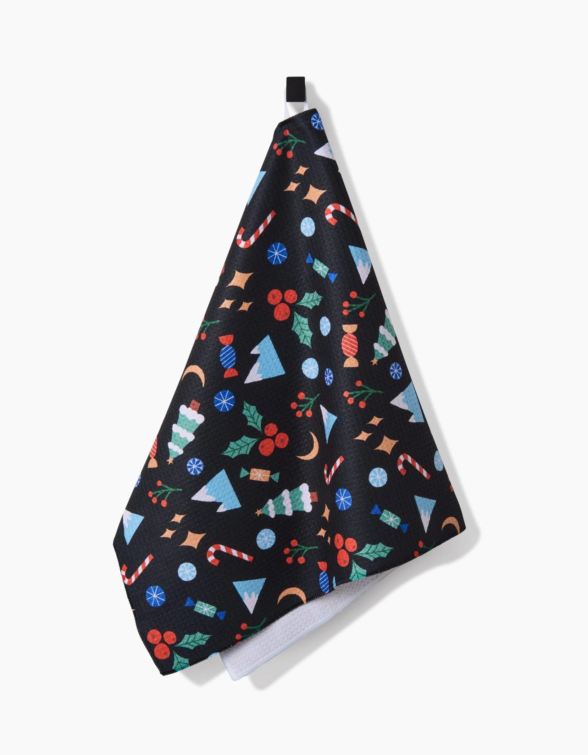 The Claire Iglesias Festive Christmas black tea towel features holiday patterns—trees, candy canes, holly, and ornaments—made from recycled materials. Ultra-absorbent and colorful, it hangs easily from a small black loop.