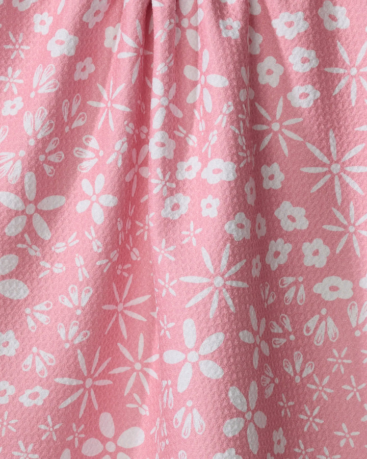 Close-up of the Hufton Studio "Fields of Flowers" tea towel, made from textured pink Geoweave fabric and adorned with a cheerful pattern of white flowers and petals in various sizes.
